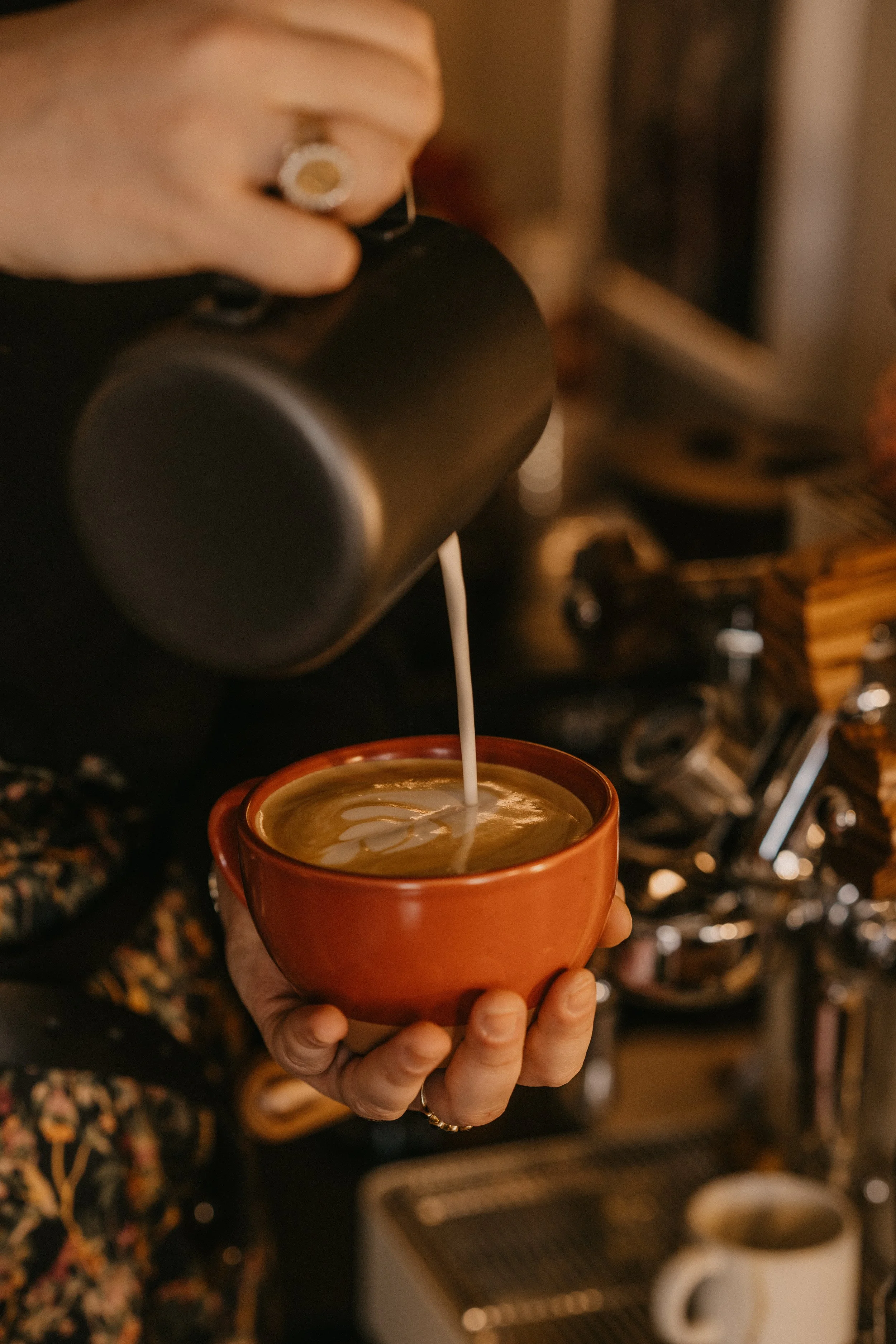 madeline pouring latte art into red mug