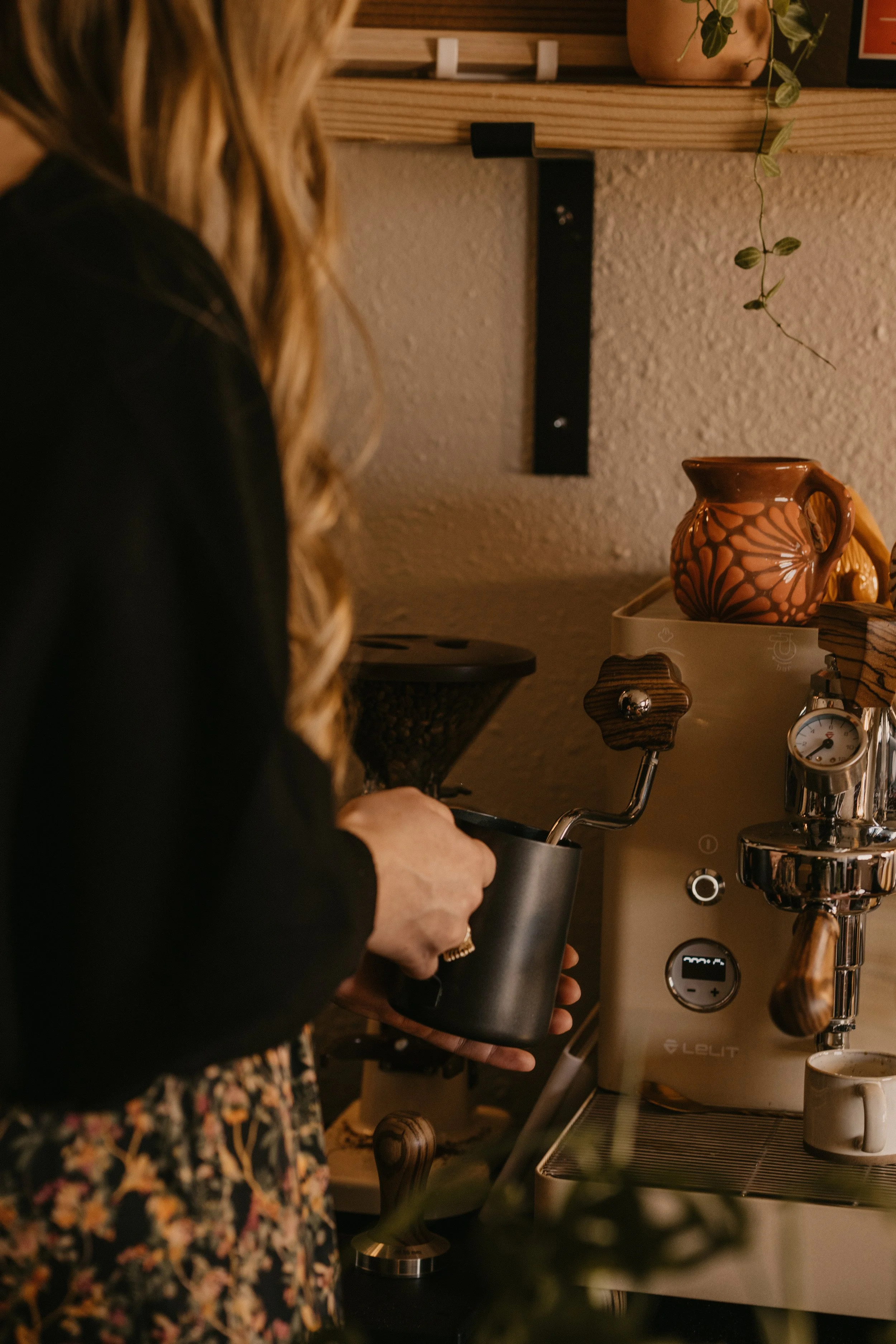 madeline steaming milk with milk pitcher in Casa Hogar office talavera mug hanging plant and sign saying Hogar dulce hogar