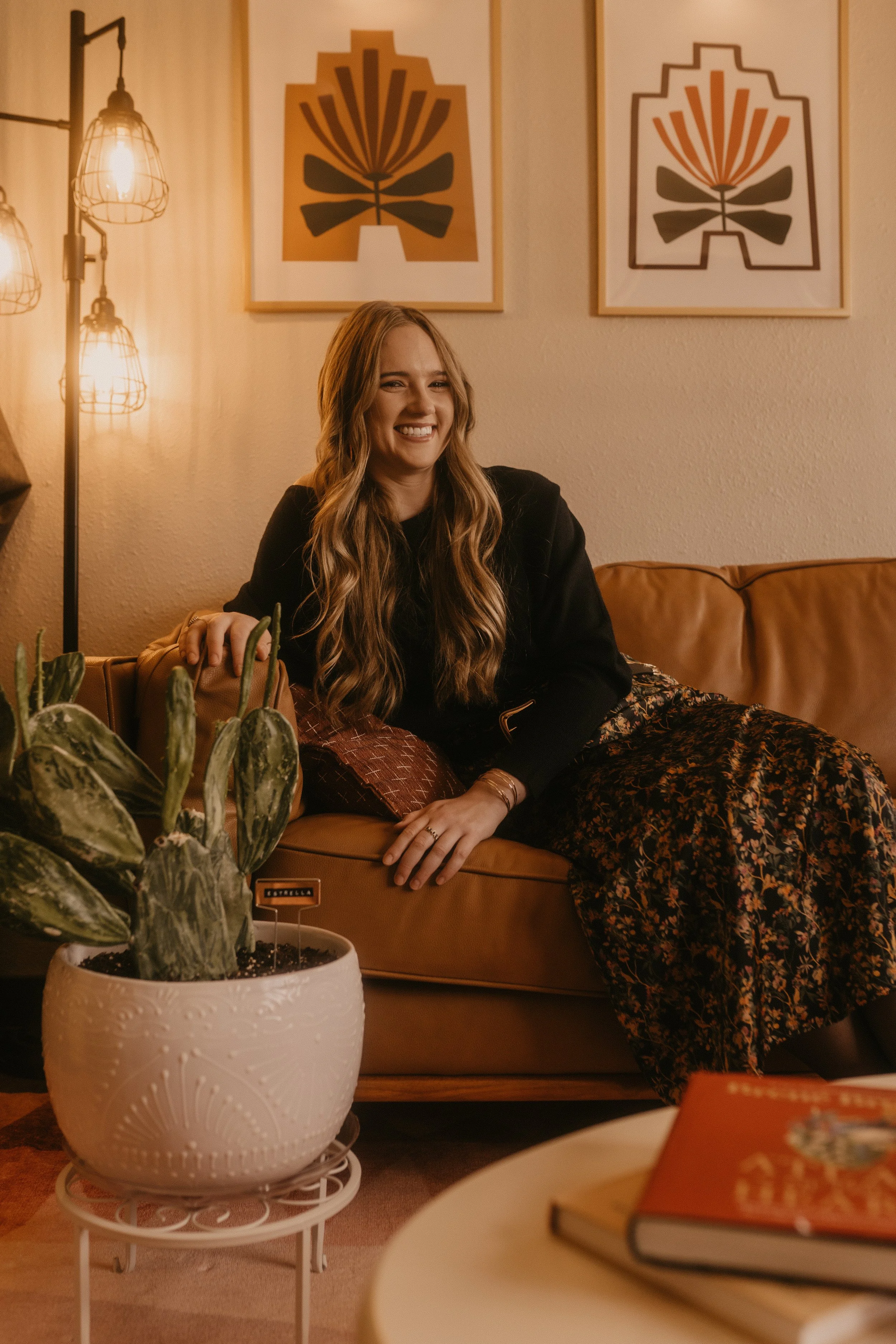 madeline sits comfortably on Casa Hogar office couch smiling at the camera for a picture