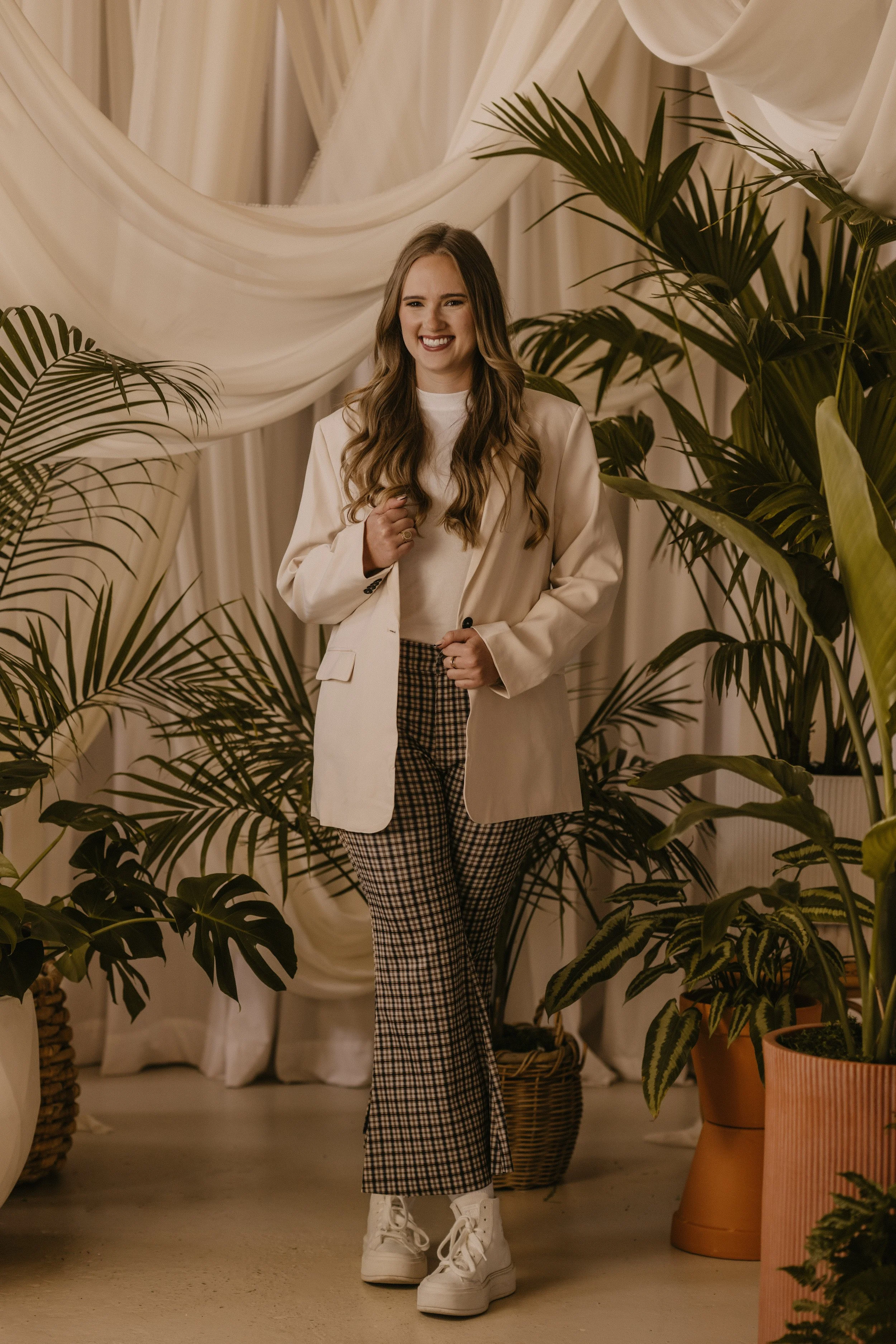 Madeline poses in studio for professional head shot with plants and pots in background