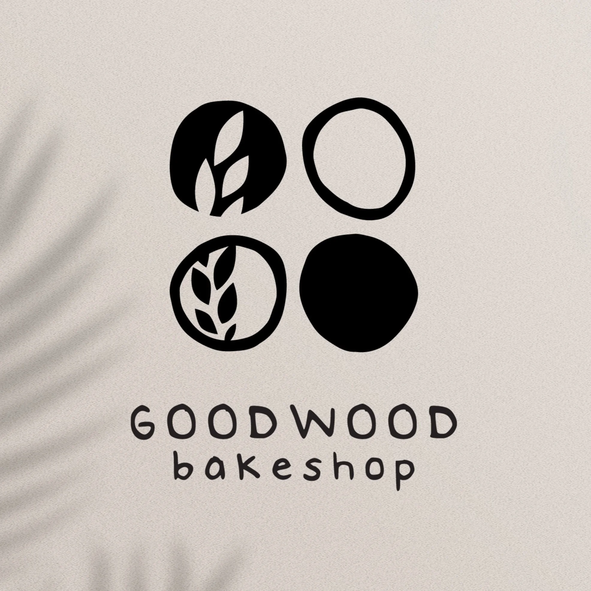 Light beige background with shadow leave with the Goodwood bakeshop logo on top
