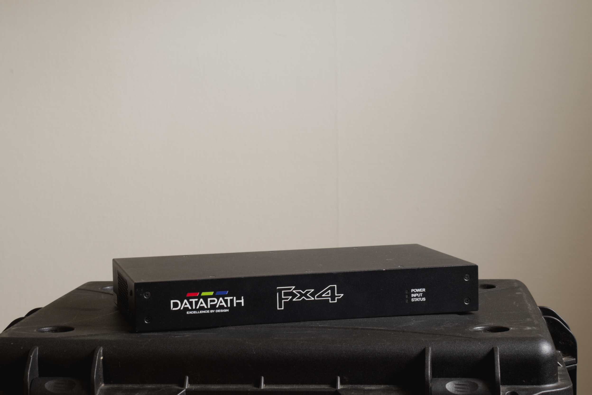 A black electronic device labeled DATAPATH FX4 with power, input, and status indicators, resting on a black plastic container.