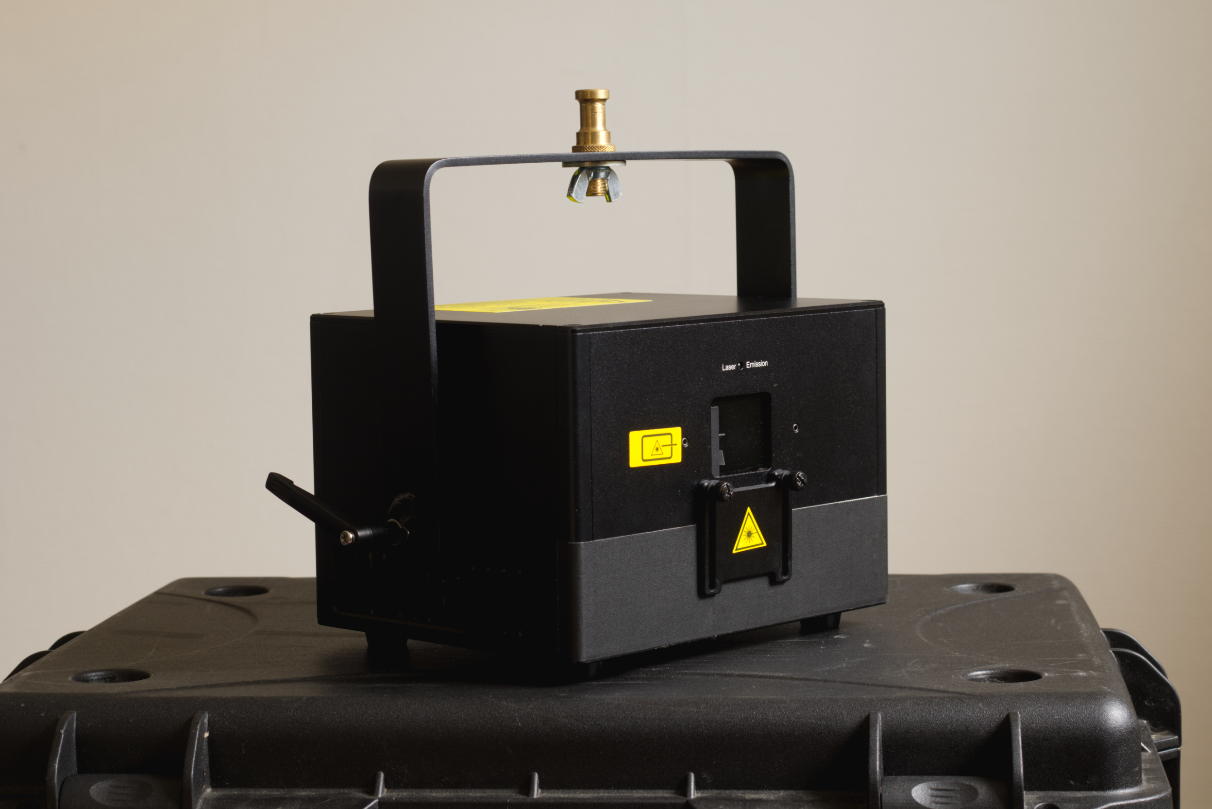 Laser engraver or cutter machine on a black plastic table with a plain light-colored wall in the background.