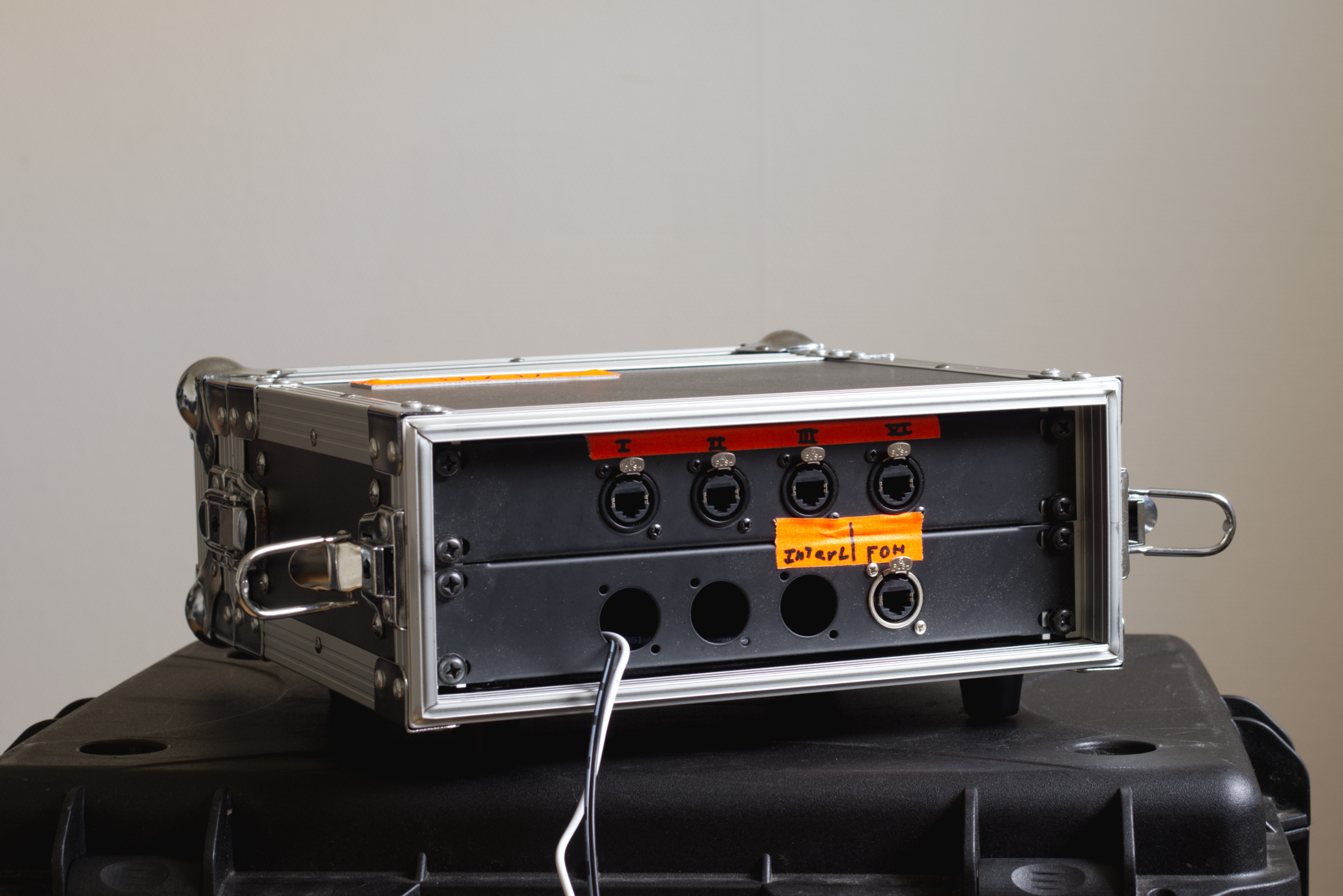 Electronics equipment with multiple circular ports and orange labels, placed on a black surface.