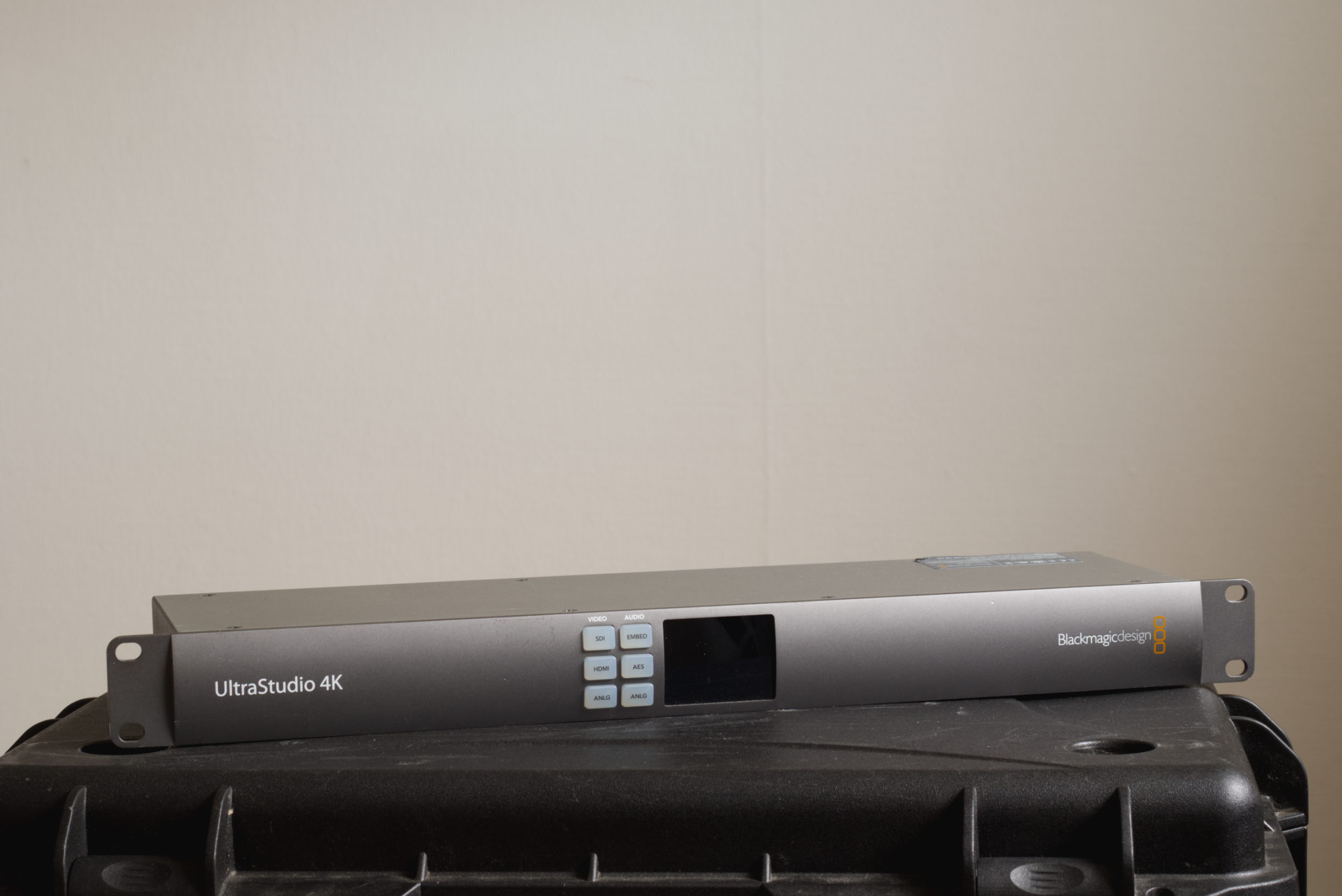 Blackmagic Design UltraStudio 4K external video interface on a black surface against a plain beige wall.