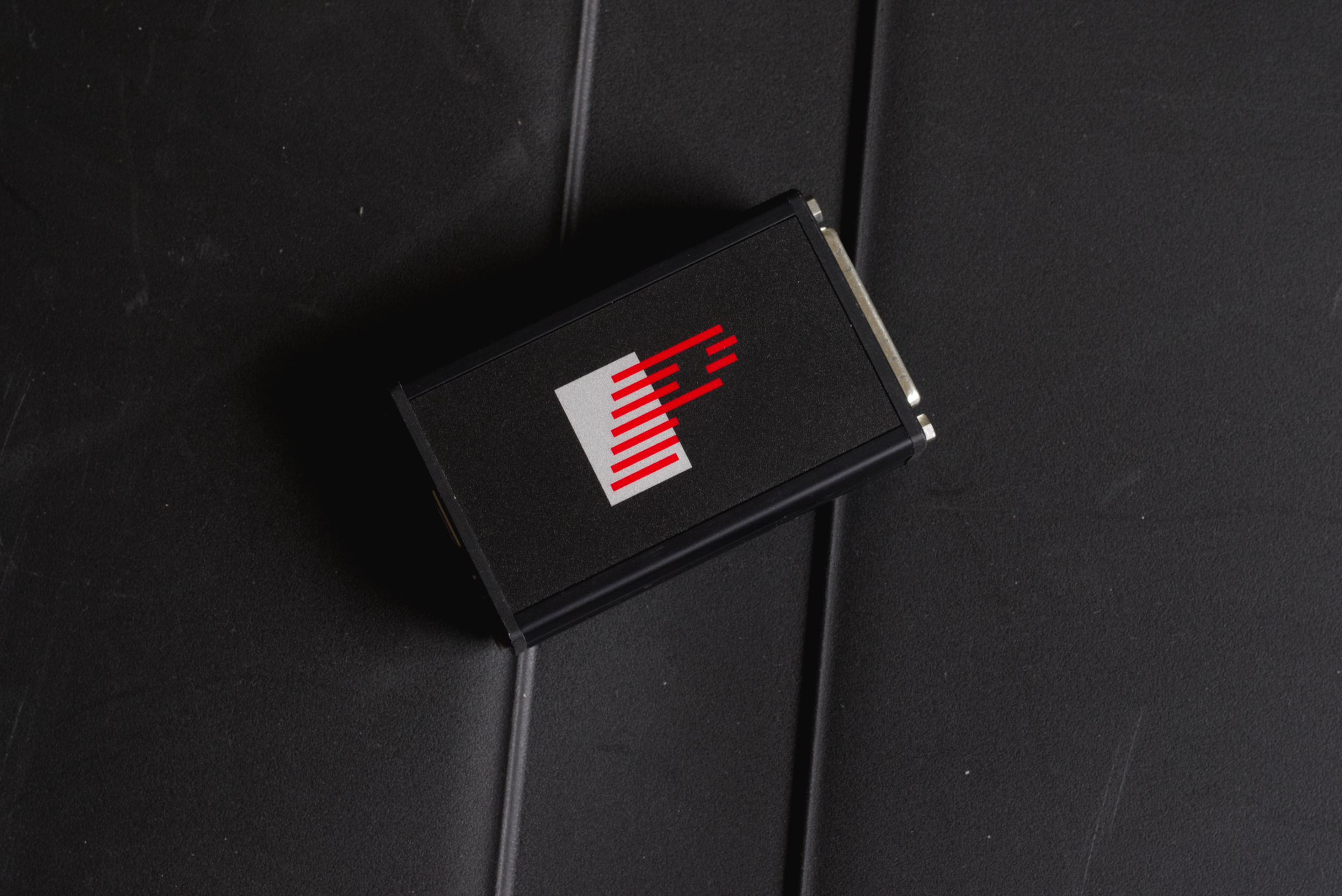 A hotel room door key card with red and white striped logo on a black background, hanging on a black textured wall.