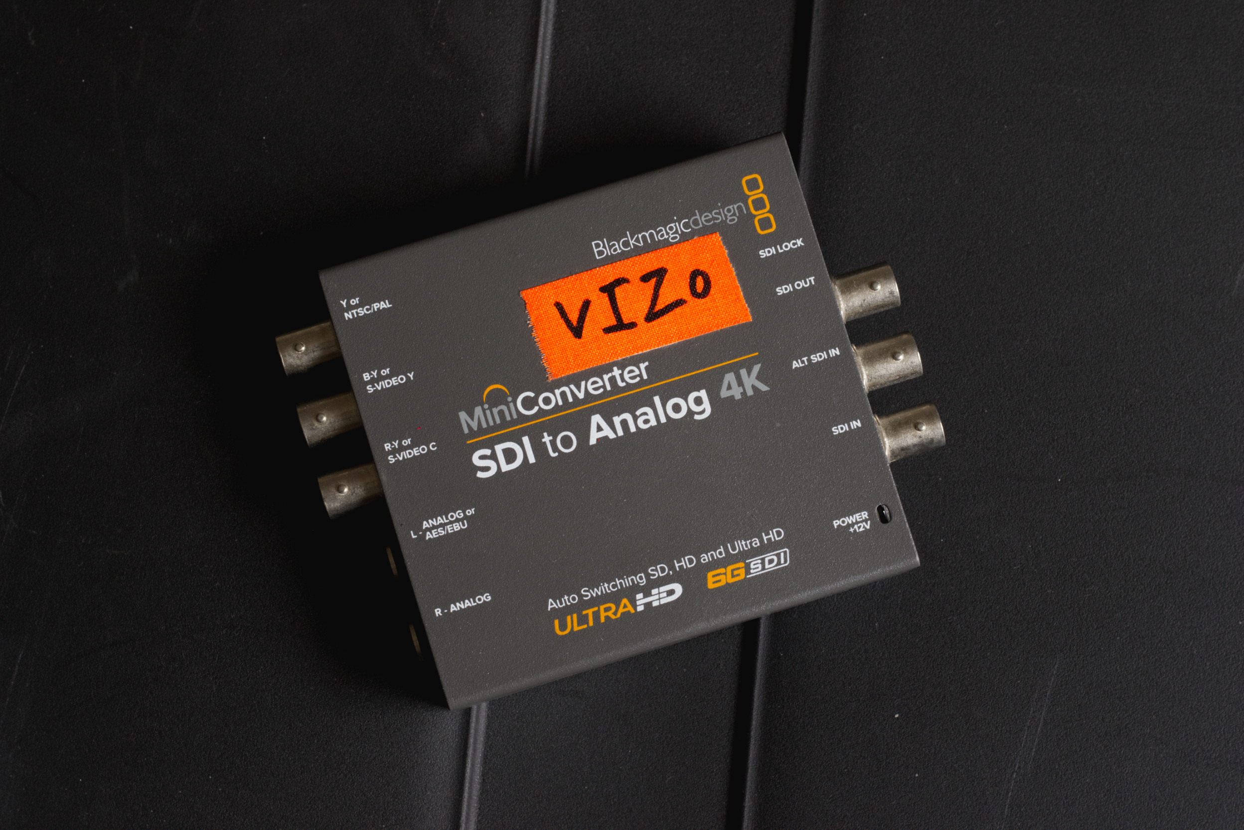 A blackmagicdesign MiniConverter SDI to Analog 4K device with a red label displaying VIZIO, placed on a black surface.