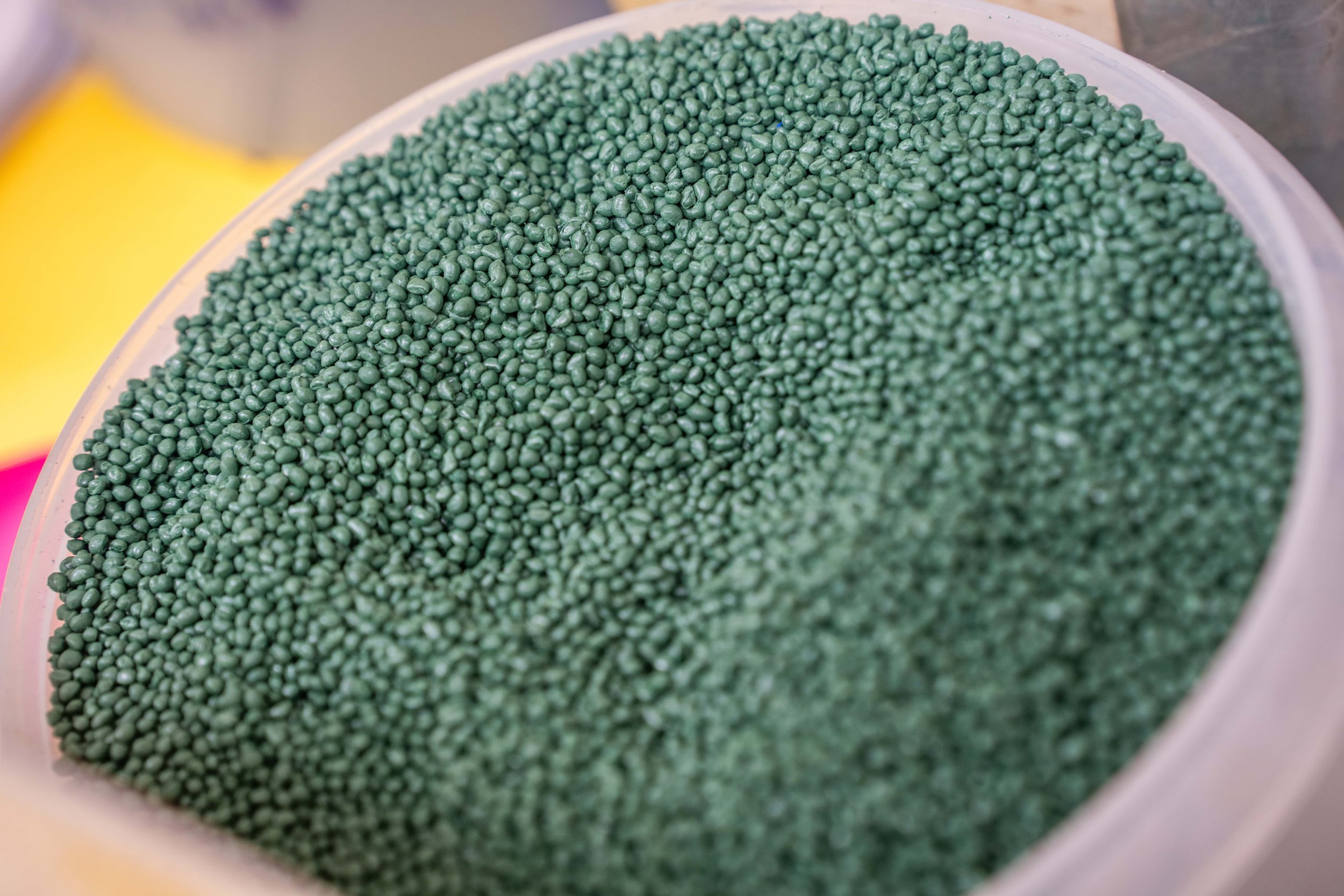 Close-up of a container filled with small green plastic pellets or beads.