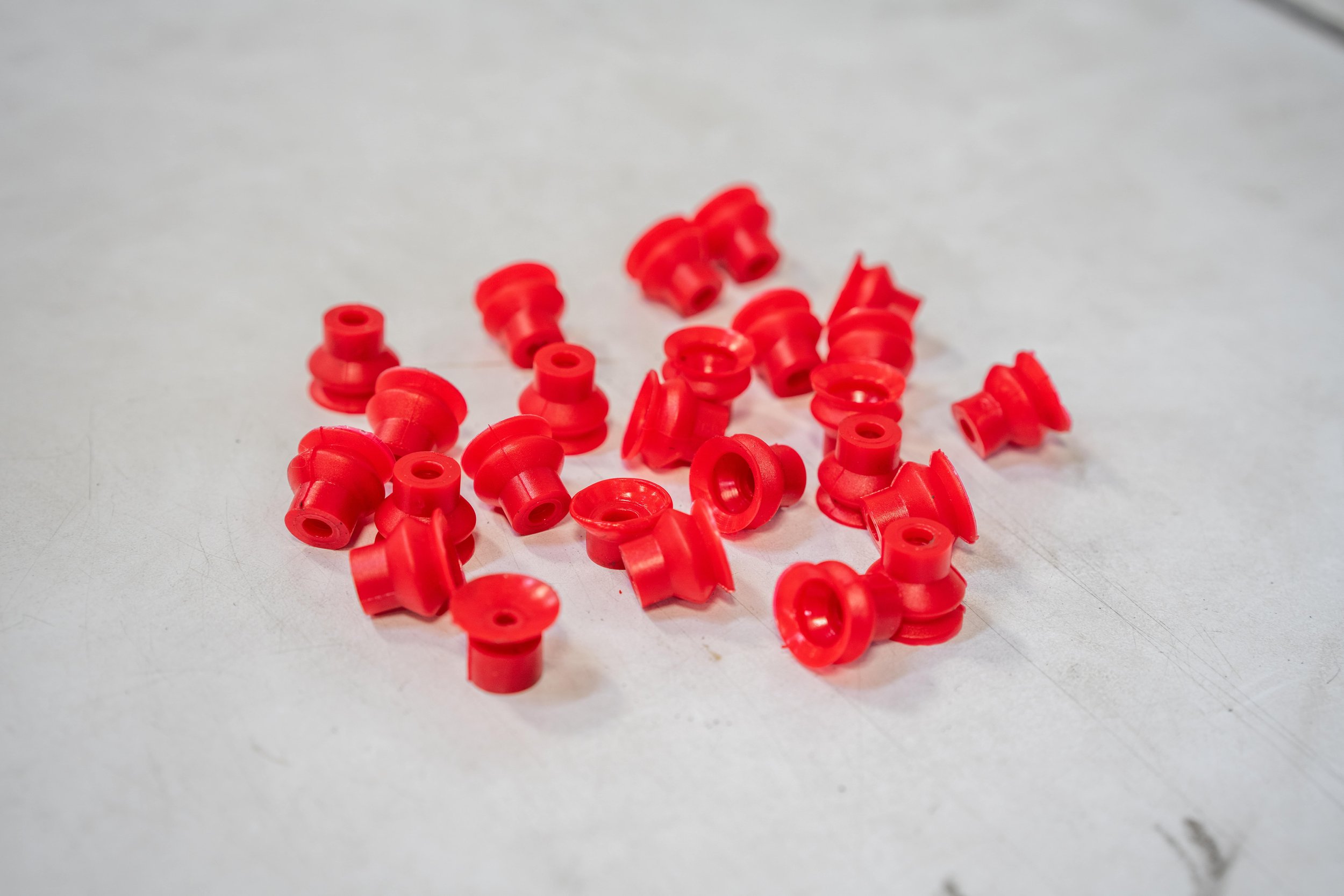 A collection of small red plastic safety goggles on a white surface.