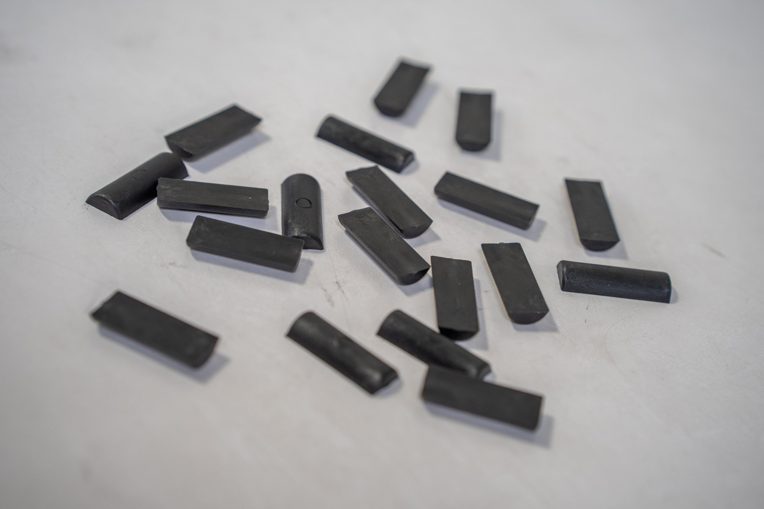 Scattered pieces of black chalk on a white surface.
