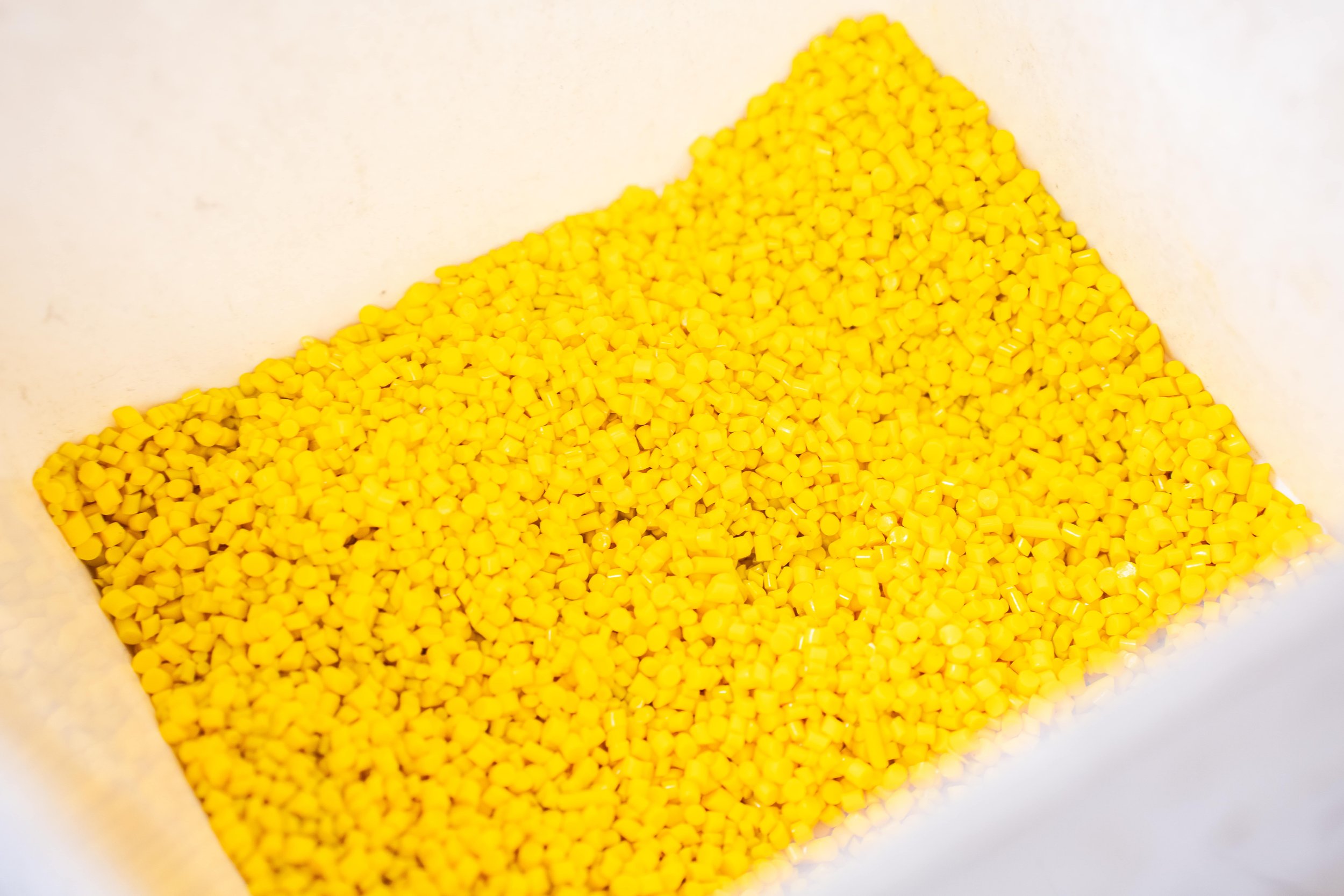 Close-up of a container filled with small yellow plastic pellets.
