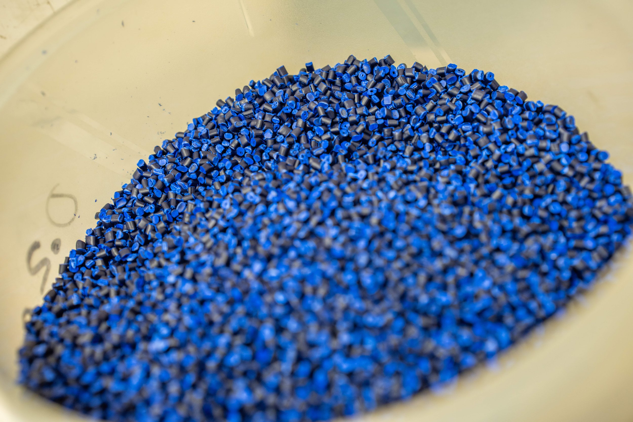 Close-up of numerous small blue plastic pellets inside a clear container.