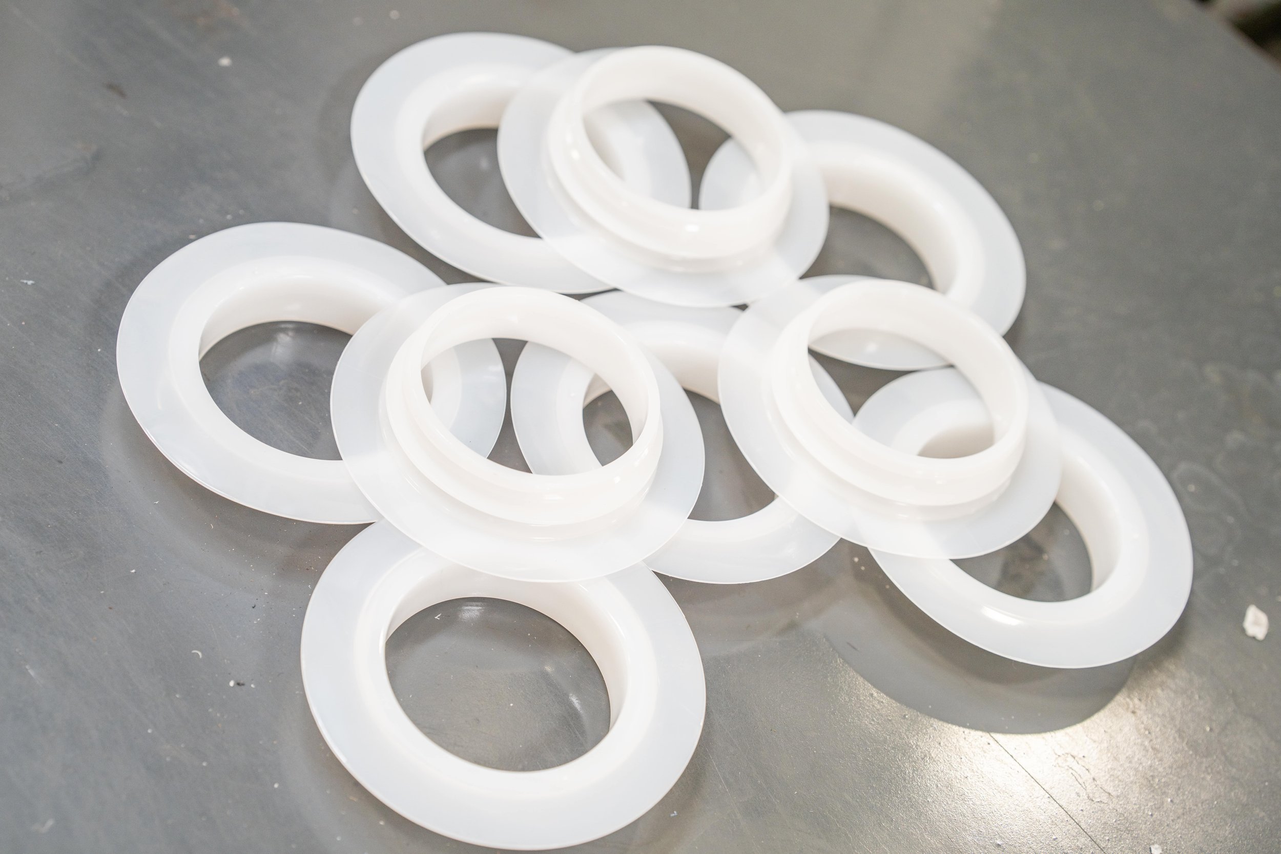 Multiple white plastic washers scattered on a dark gray surface.