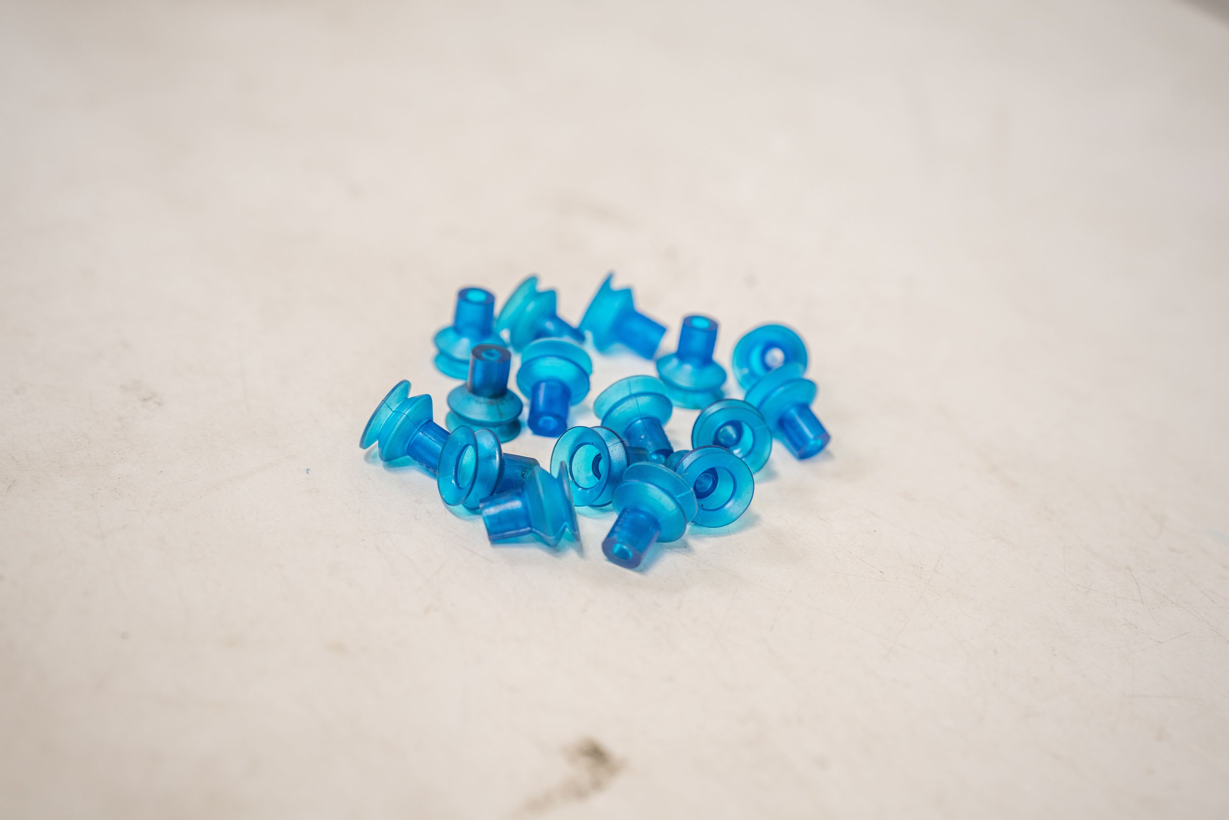 Small blue plastic caps or Nozzles scattered on a white surface.