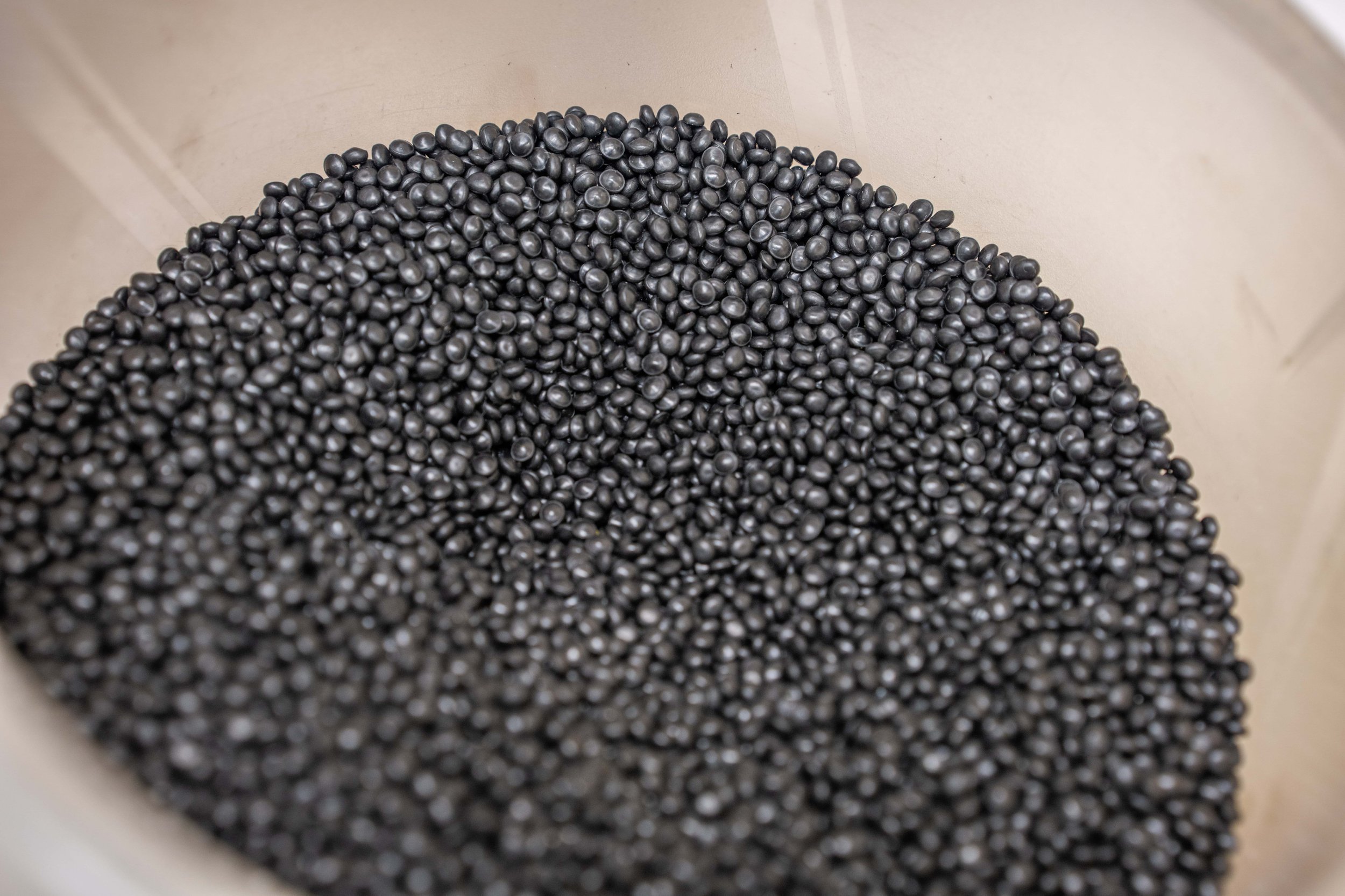 Close-up of black plastic pellets inside a container.