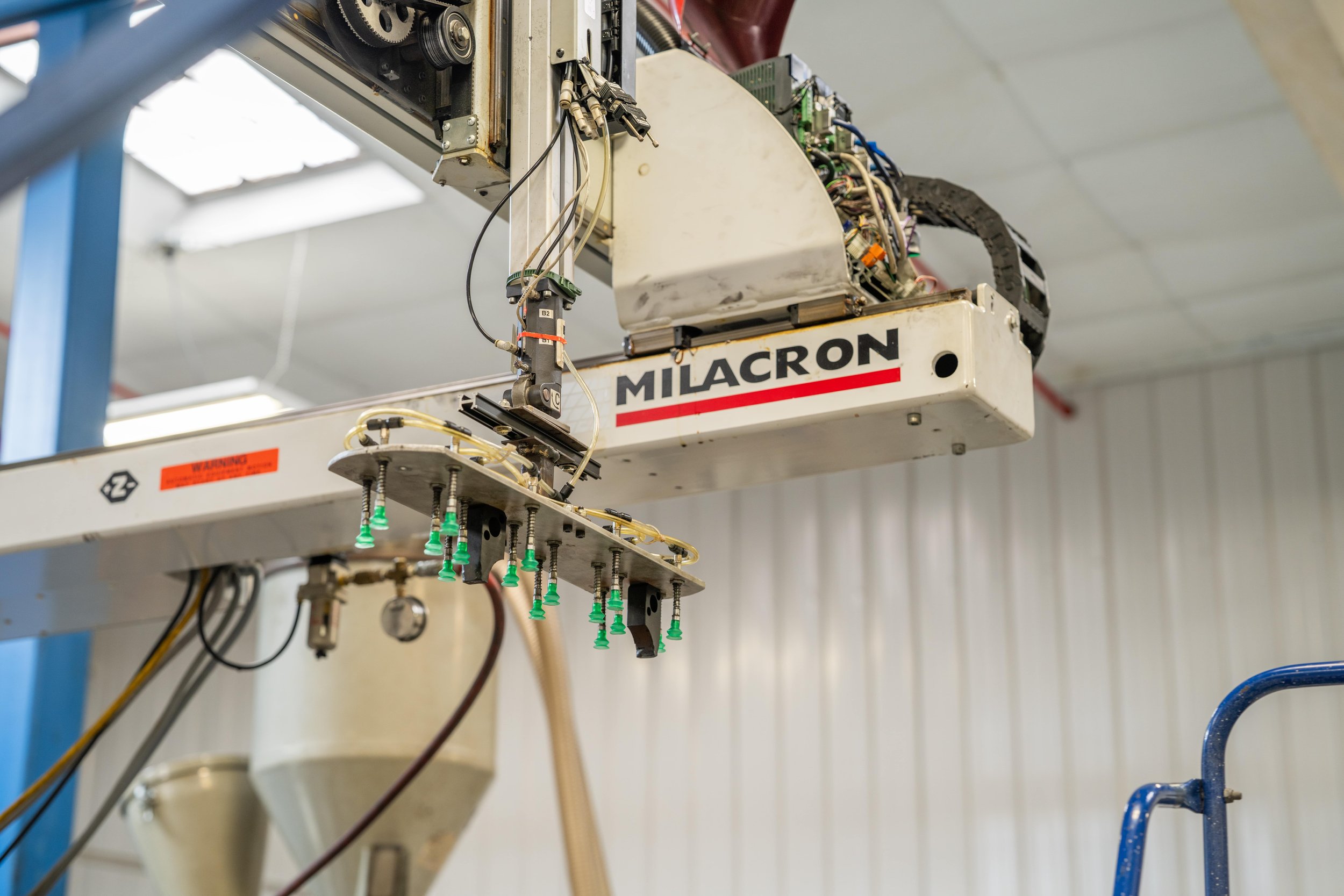 Industrial machinery with the brand name Milacron in a factory setting.
