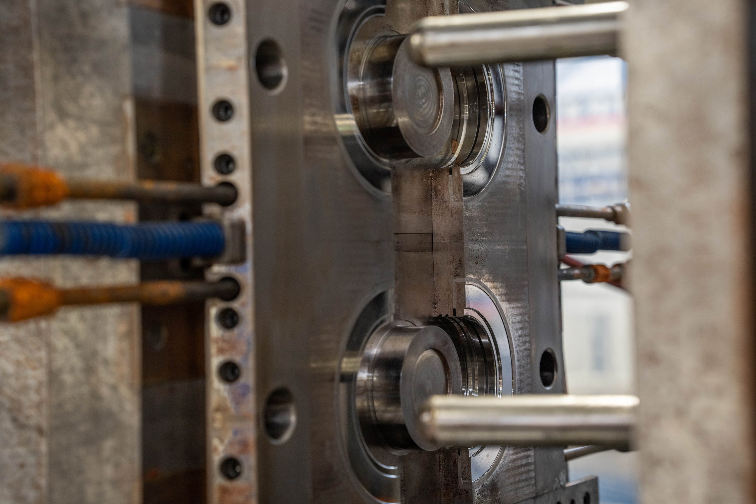 Close-up of a metal industrial machine part with bolts and rods, likely used in manufacturing or engineering.