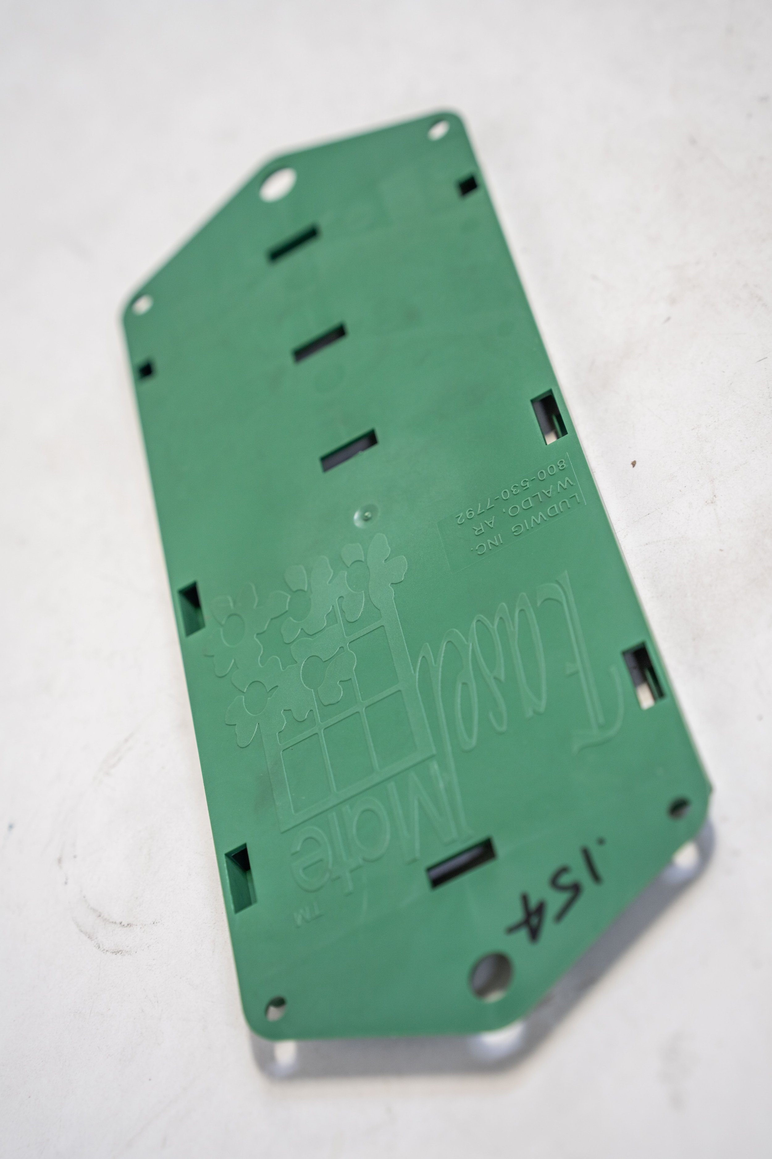 A green plastic electronic circuit component with the words "Mobile 154" written on it, resting on a white surface.
