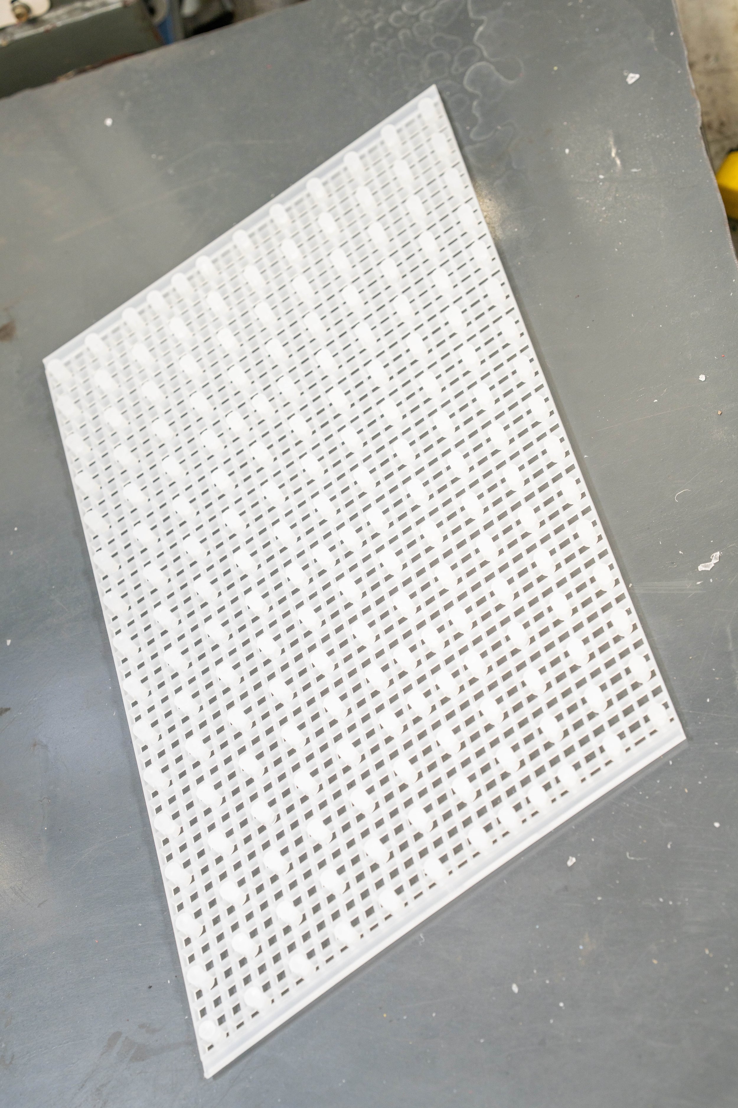 A white plastic grid or tray with multiple small compartments, placed on a gray surface.