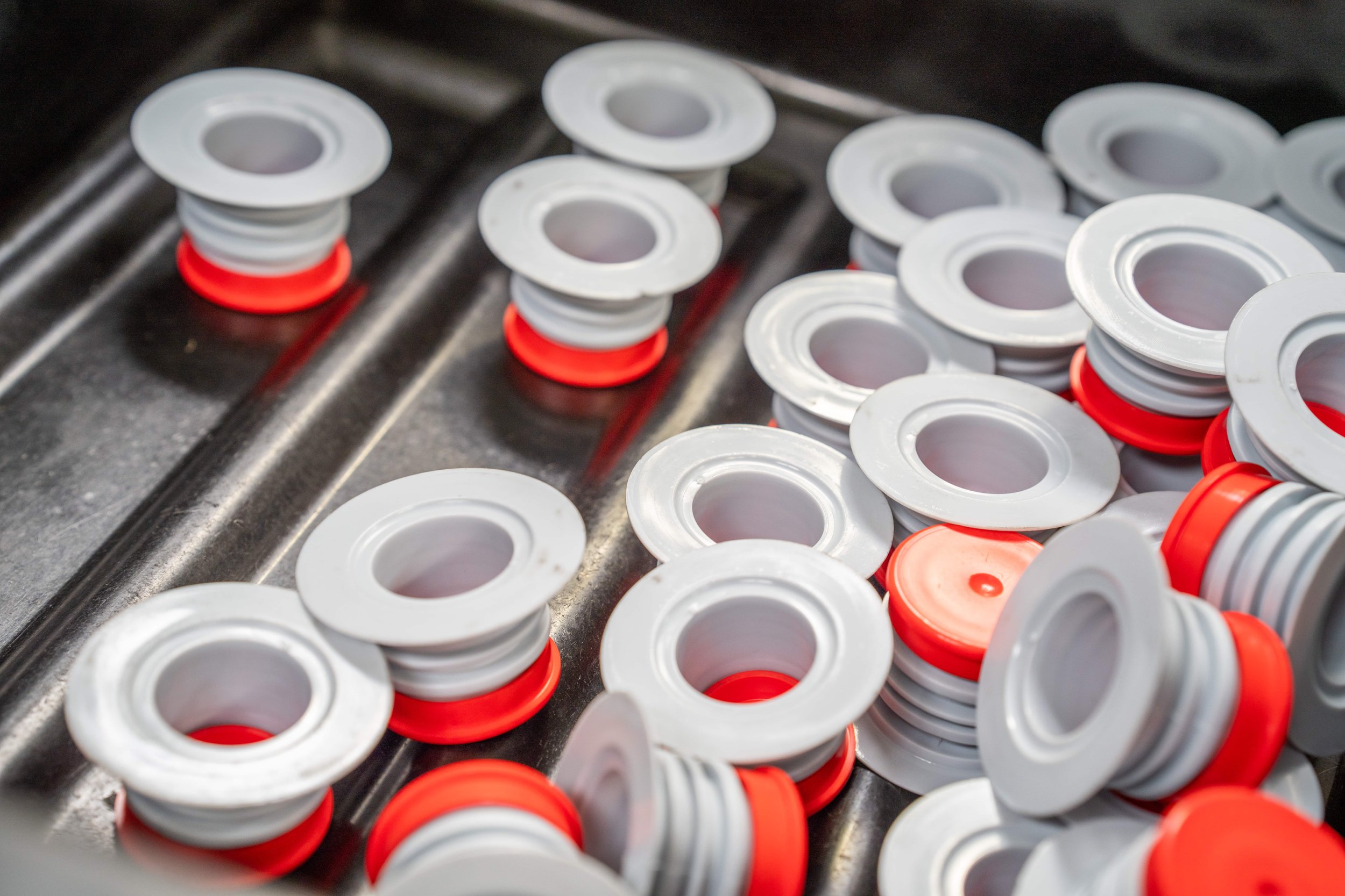 Multiple plastic Spacers with white and red colors on a metallic surface.