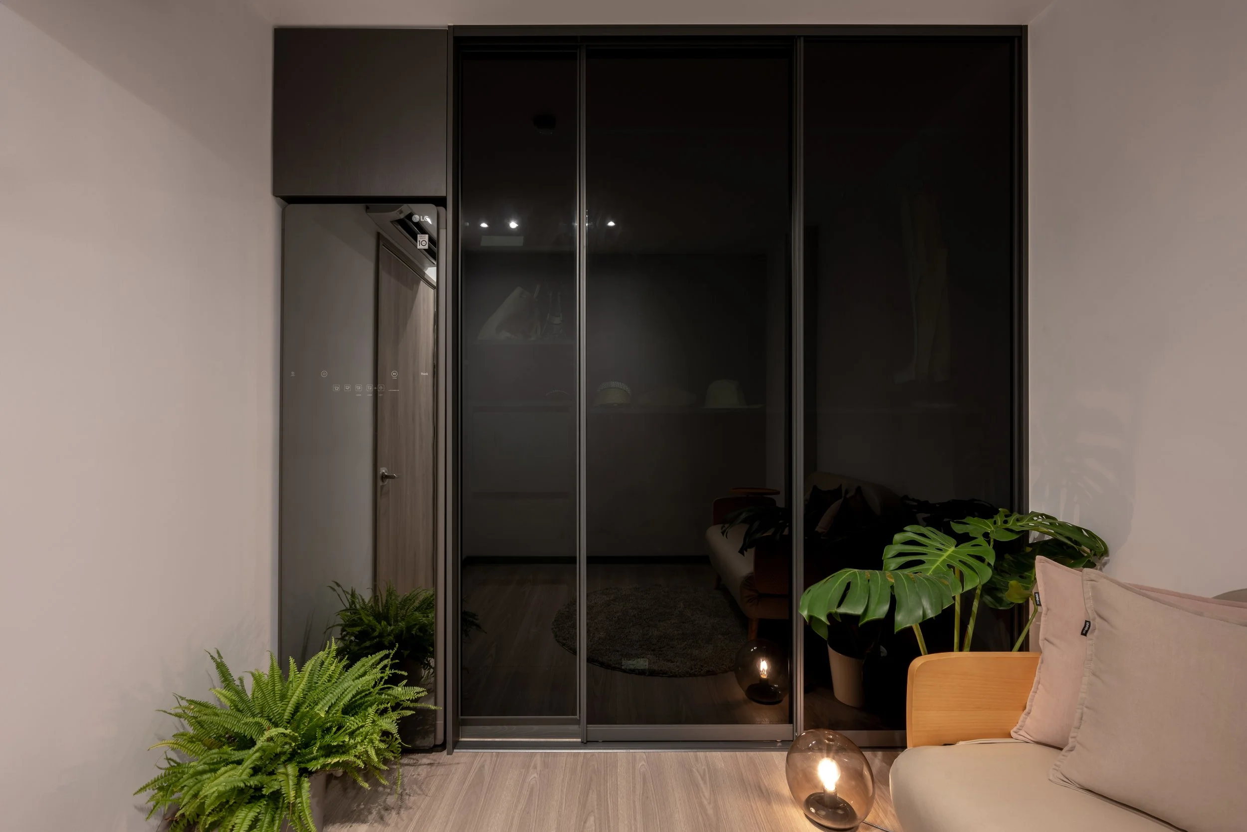 Living room with black sliding glass door, beige sofa, potted plants, and two glass table lamps on the floor.