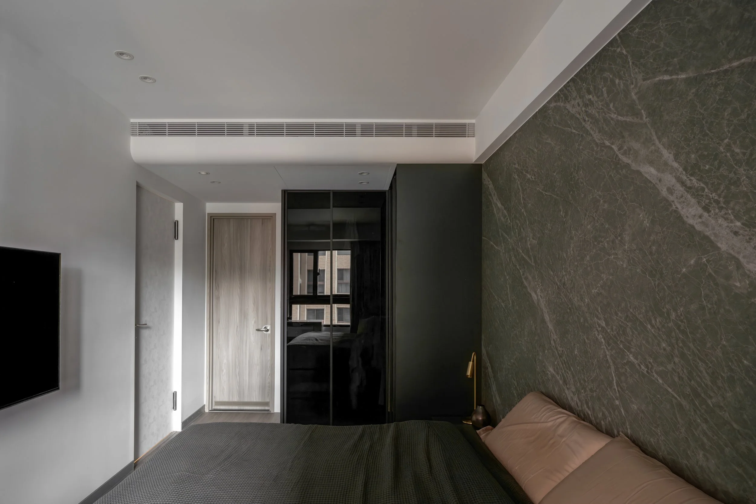 Modern bedroom with gray and black furniture, marble accent wall, and minimal decor.