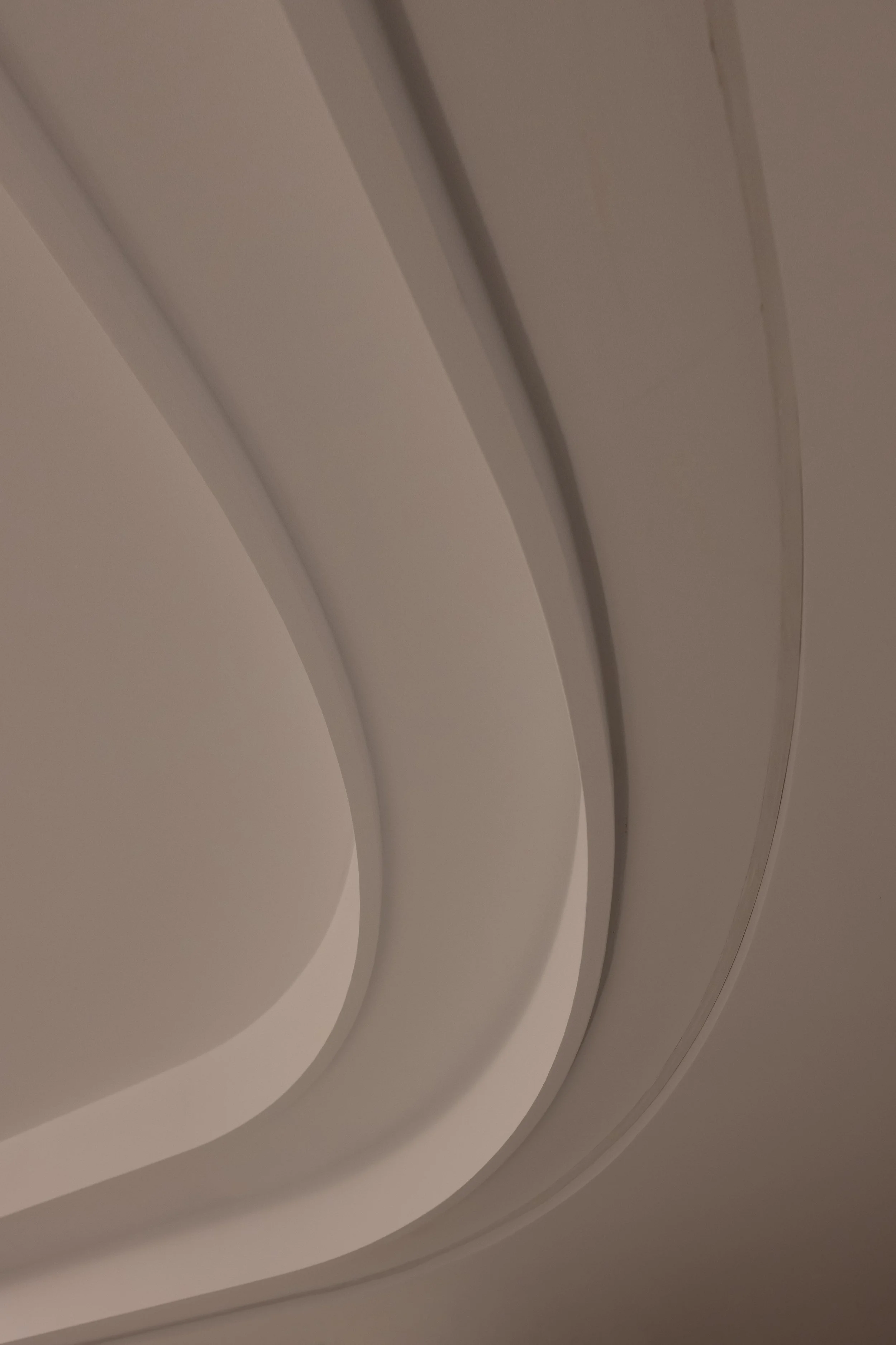 Close-up of a modern, curved ceiling with layered architectural design in neutral tones.