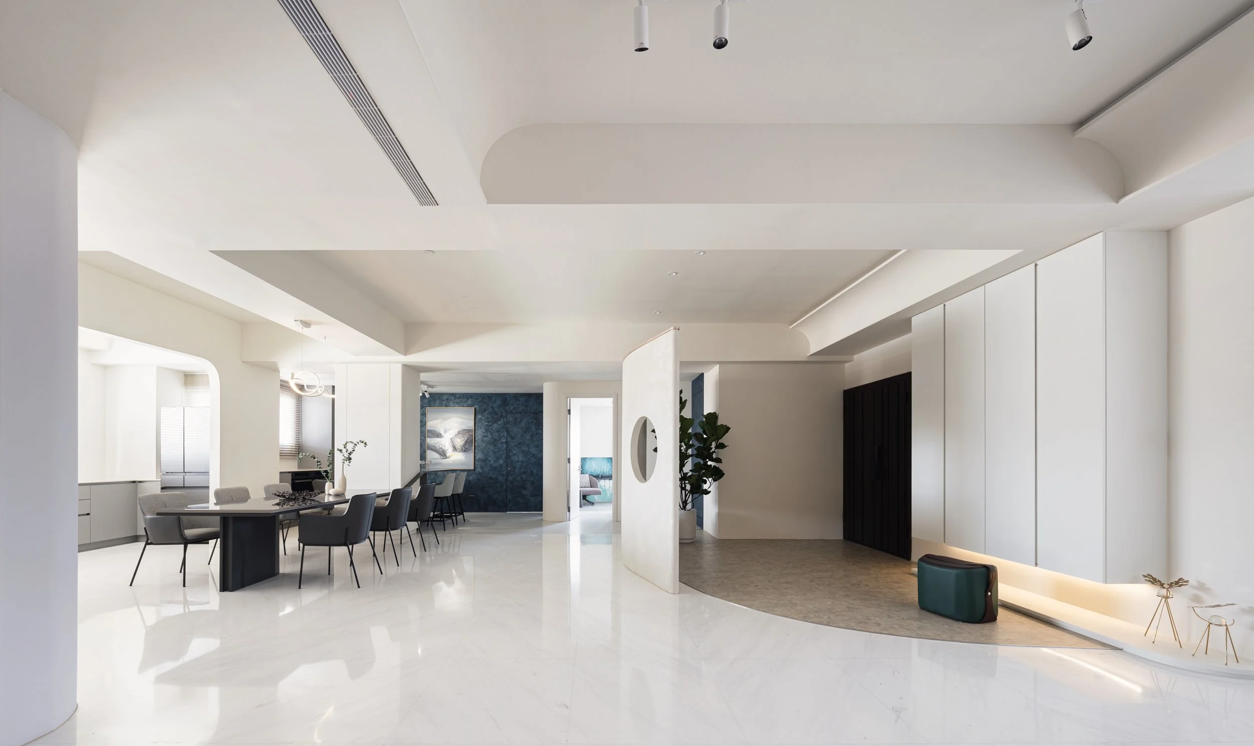 Modern open-concept living space with dining area, white walls, marble floors, and minimal decor.