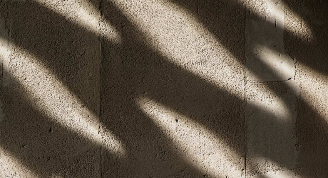 Sunlight casting diagonal shadows on a textured beige wall.