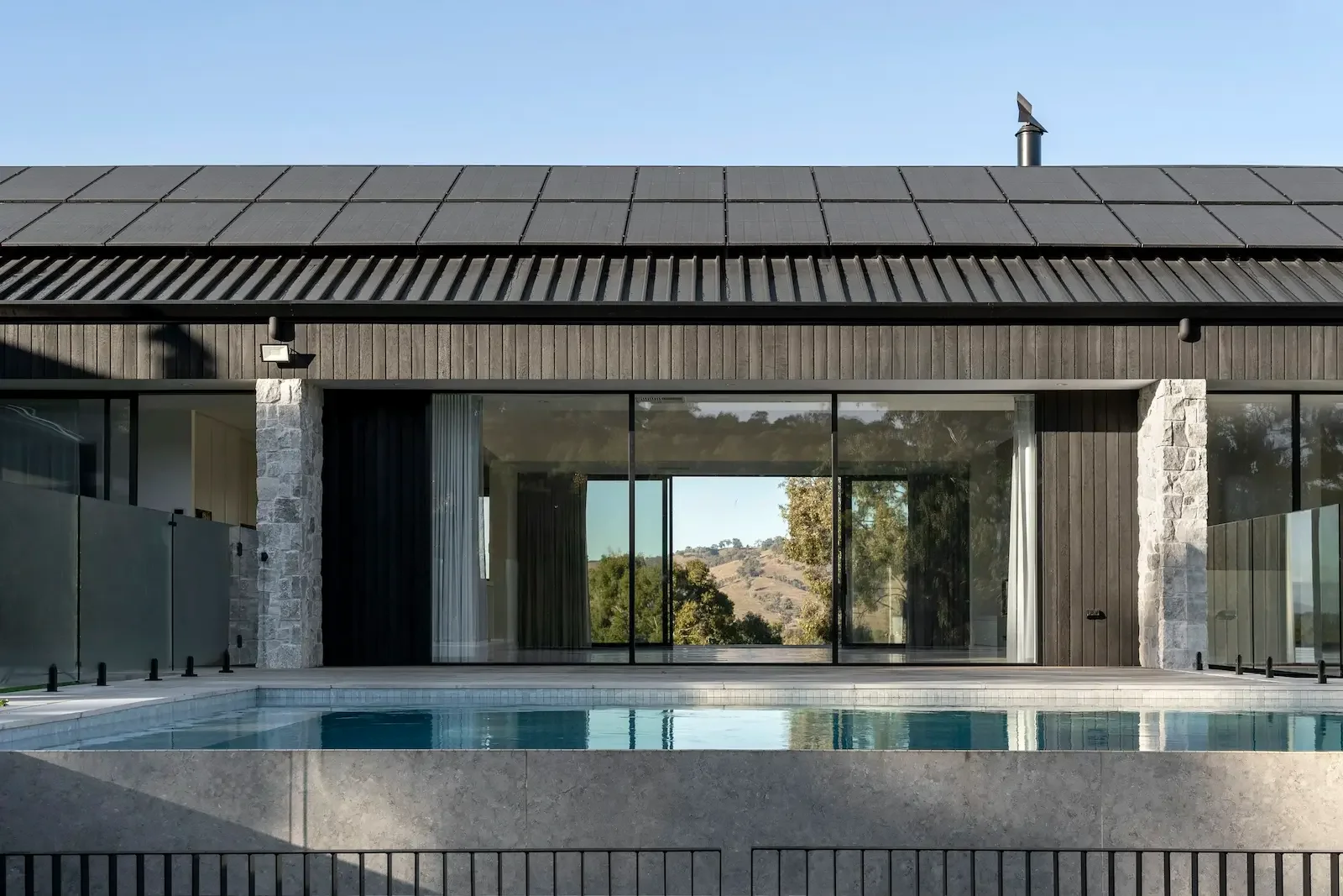 Exterior view of a modern single-story home featuring a dark corrugated metal roof