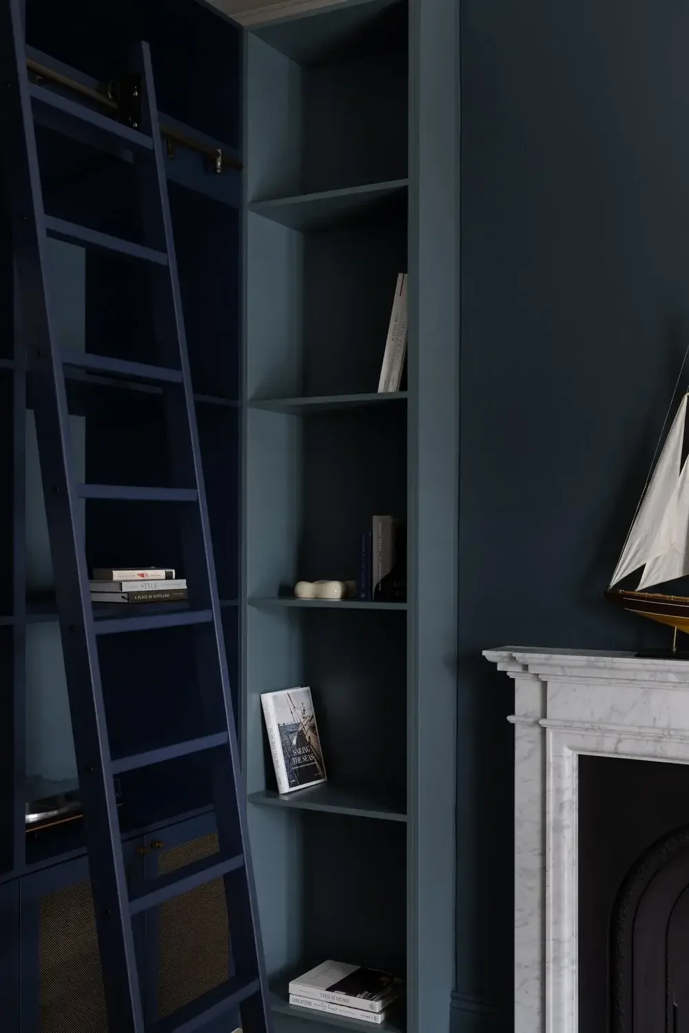 Dark blue built-in bookshelves with a rolling library