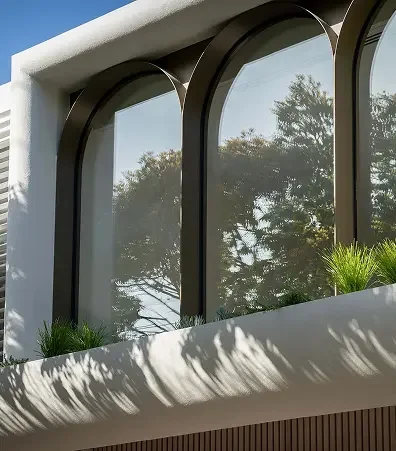 Architectural exterior detail featuring large arched windows with dark metal frames,
