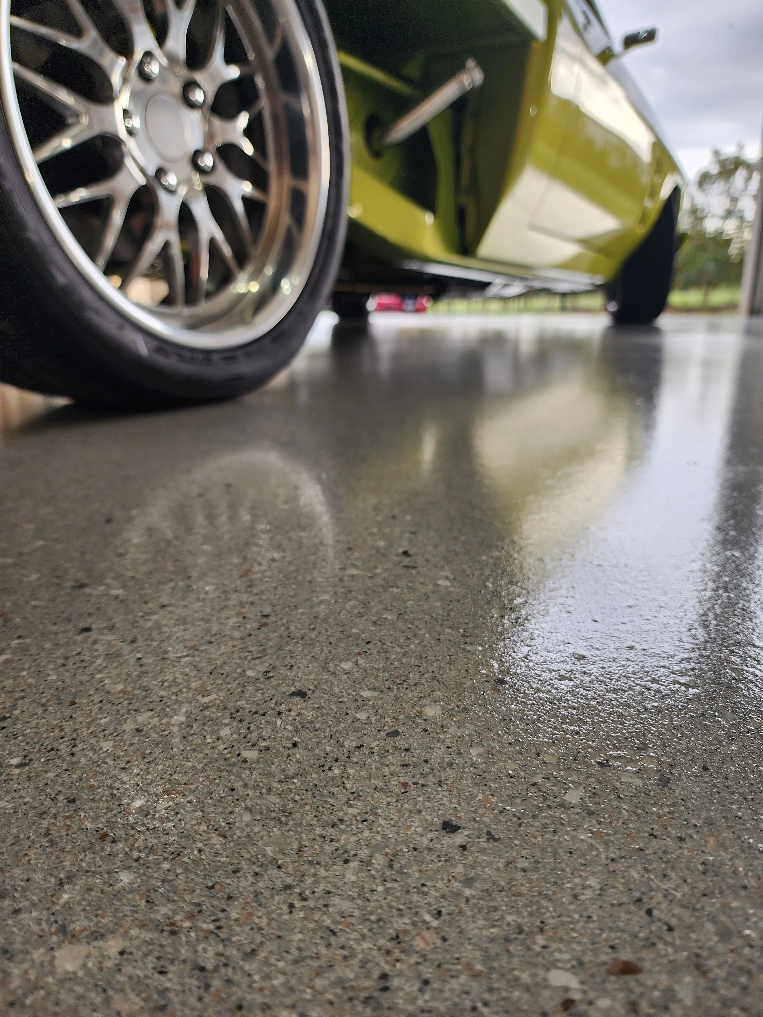Close-up of a green sports car with a focus on the front wheel on a floor with a Hyper Flake epoxy coating.