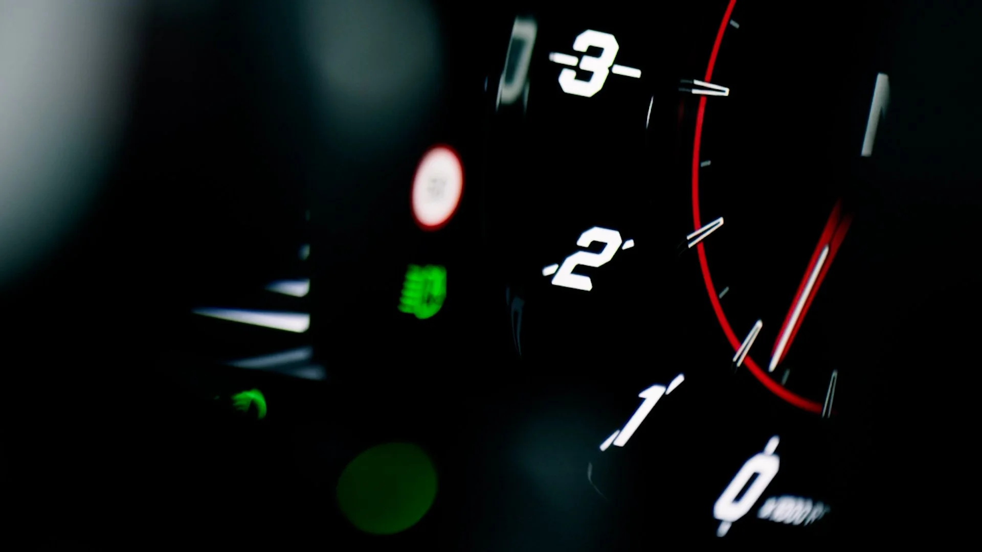 Close-up of a car dashboard showing the speedometer, tachometer, and warning lights in a dark environment with illuminated gauges.