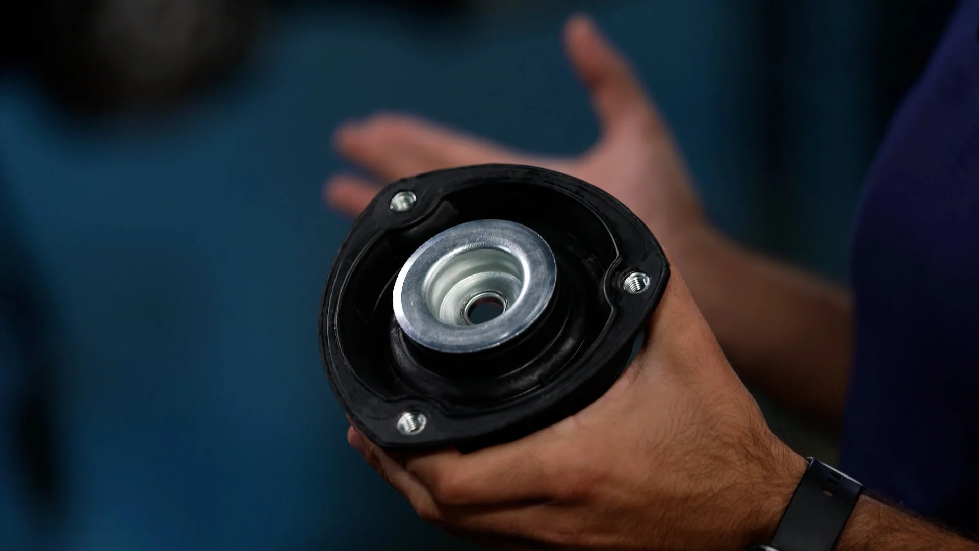 Person holding a mechanical component, likely a part of a machine or vehicle.