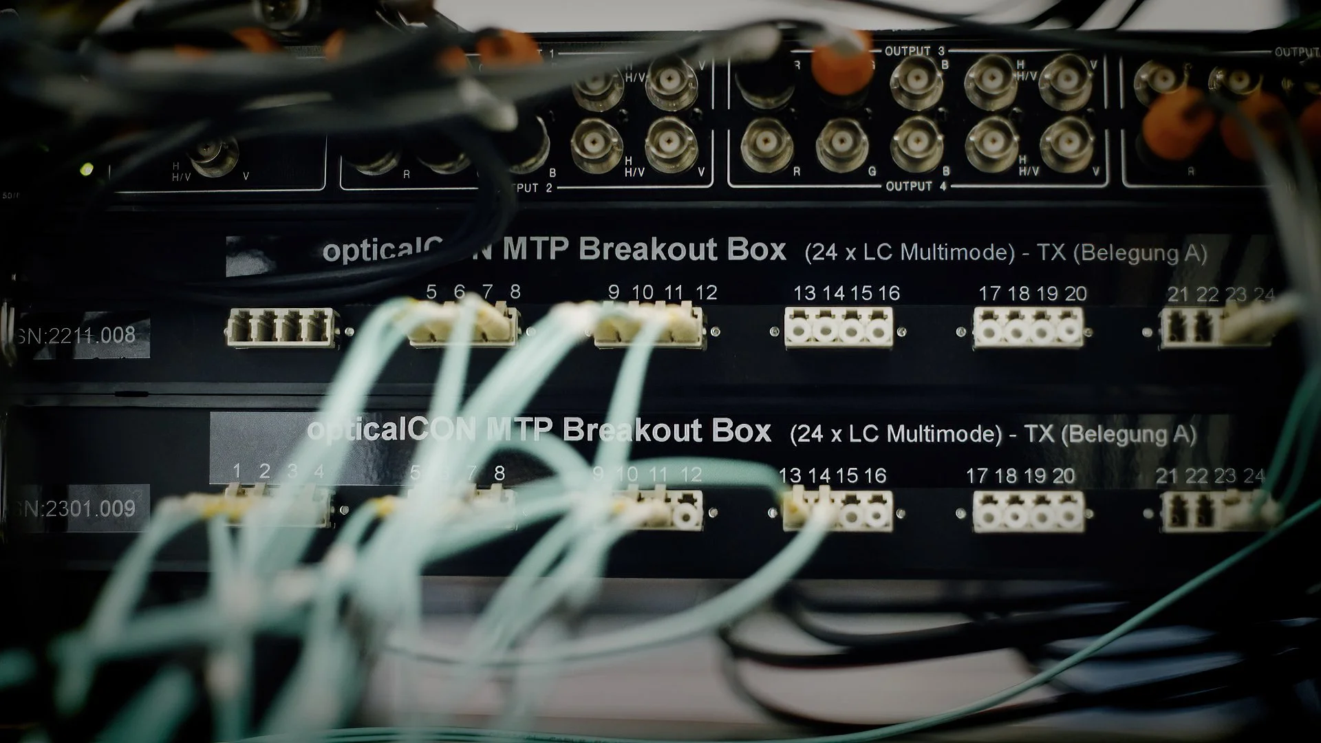 Close-up of a network patch panel with multiple Ethernet cables connected, labeled as opticalCON MTP Breakout Box.