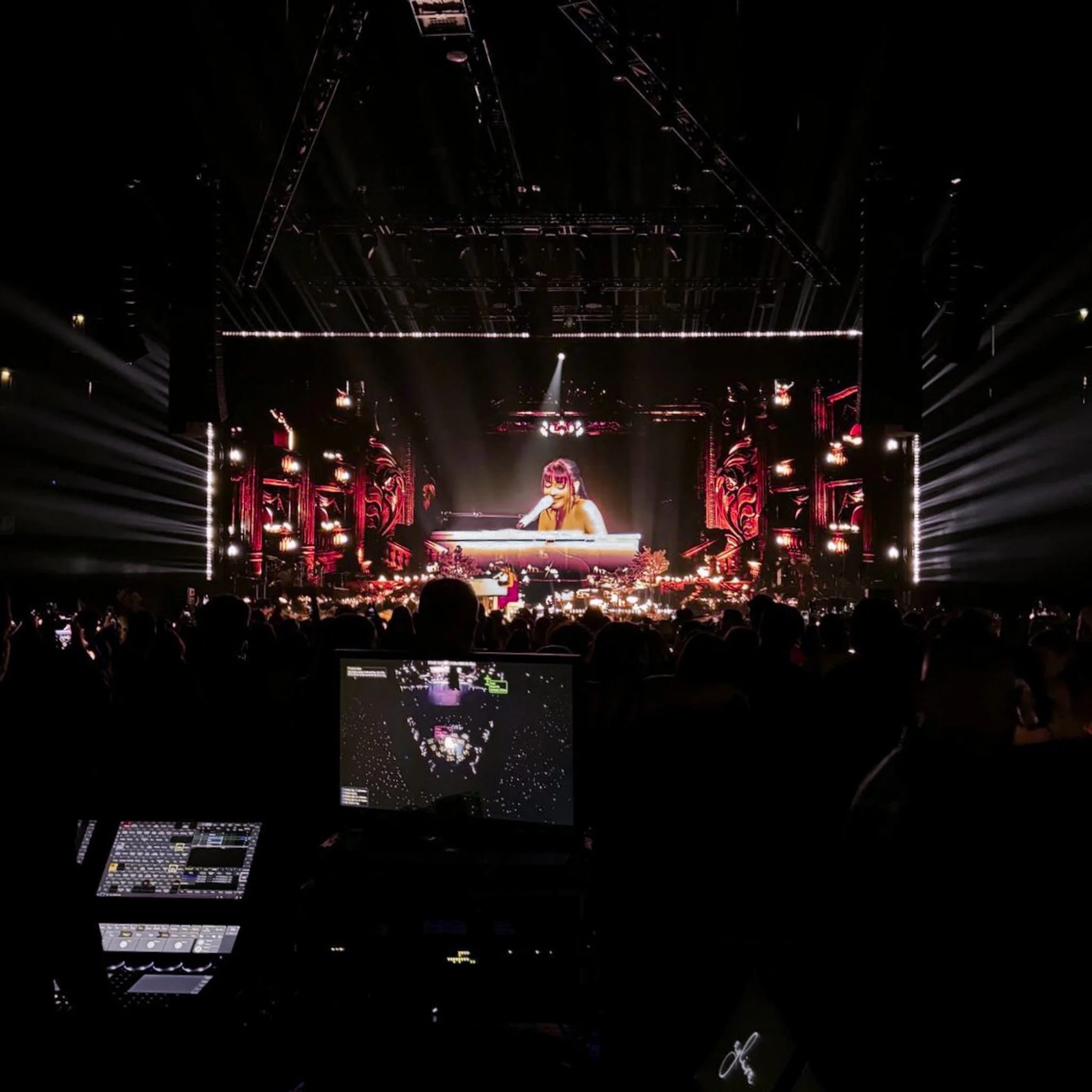 Concert scene with a performer on stage, large screen showing a close-up of the performer, audience in front, and lighting effects.