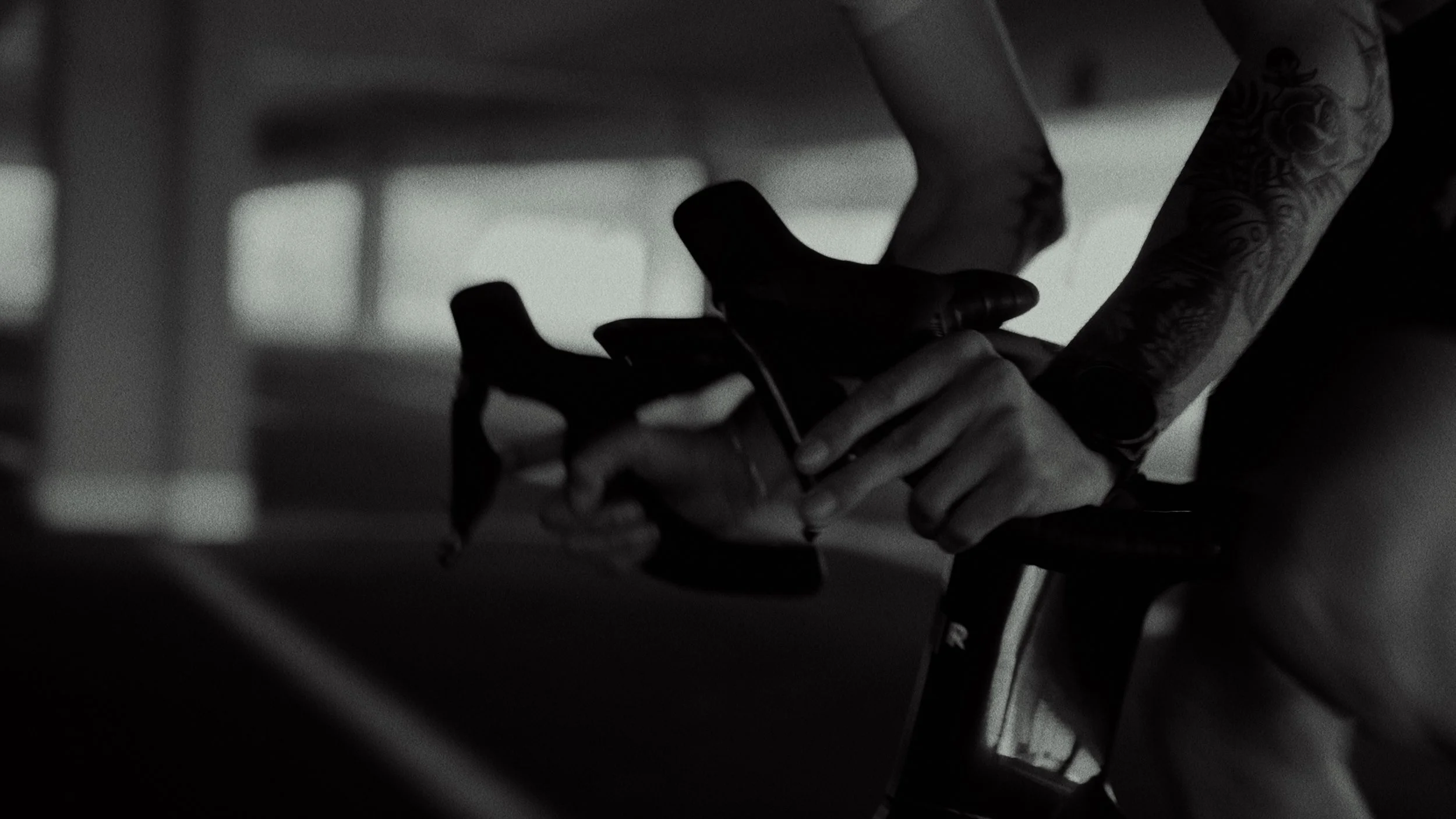 A person with tattooed arms adjusting a bicycle seat in a dimly lit indoor space.