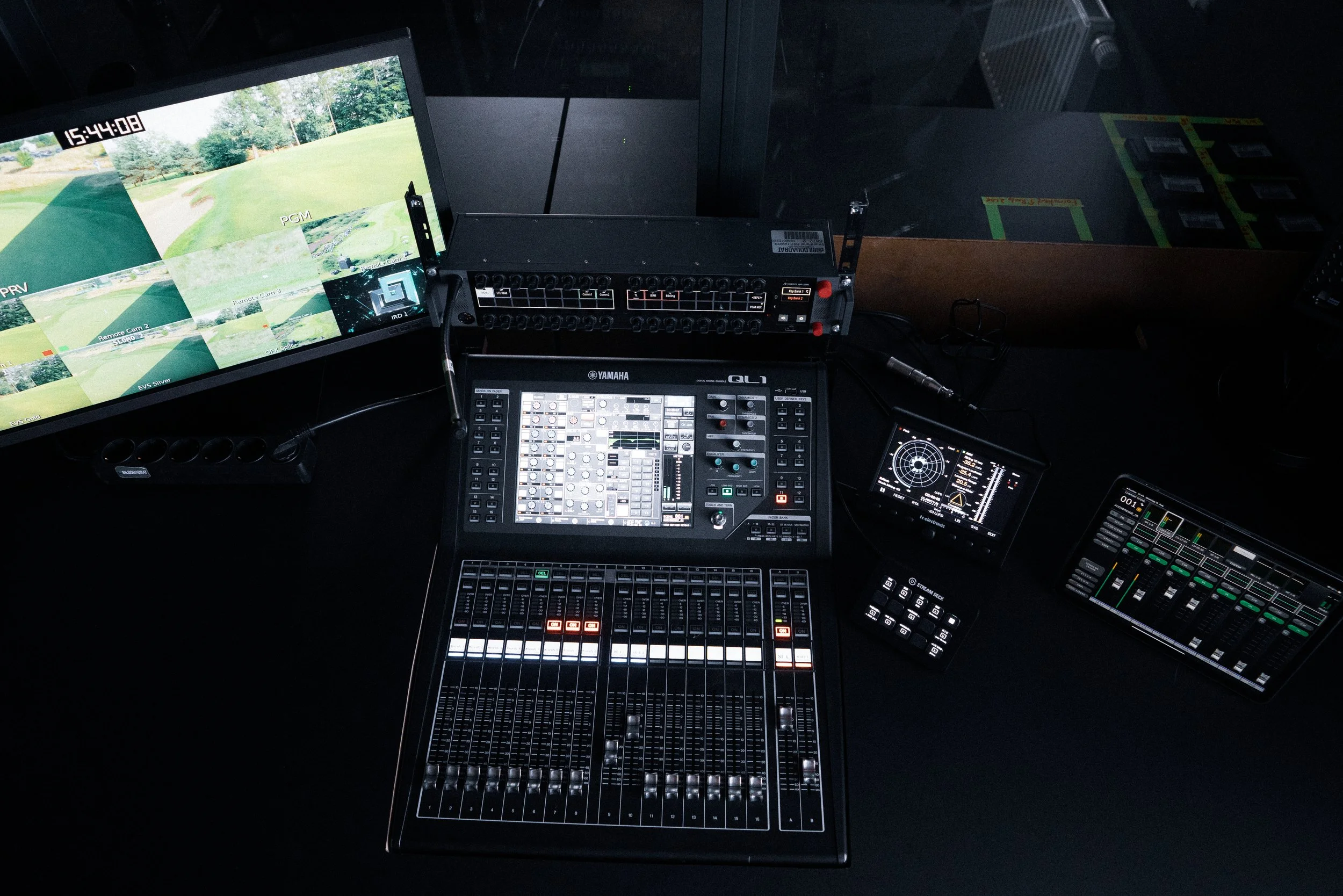 A sound mixing console and electronic equipment setup for audio control and production in a dark room.