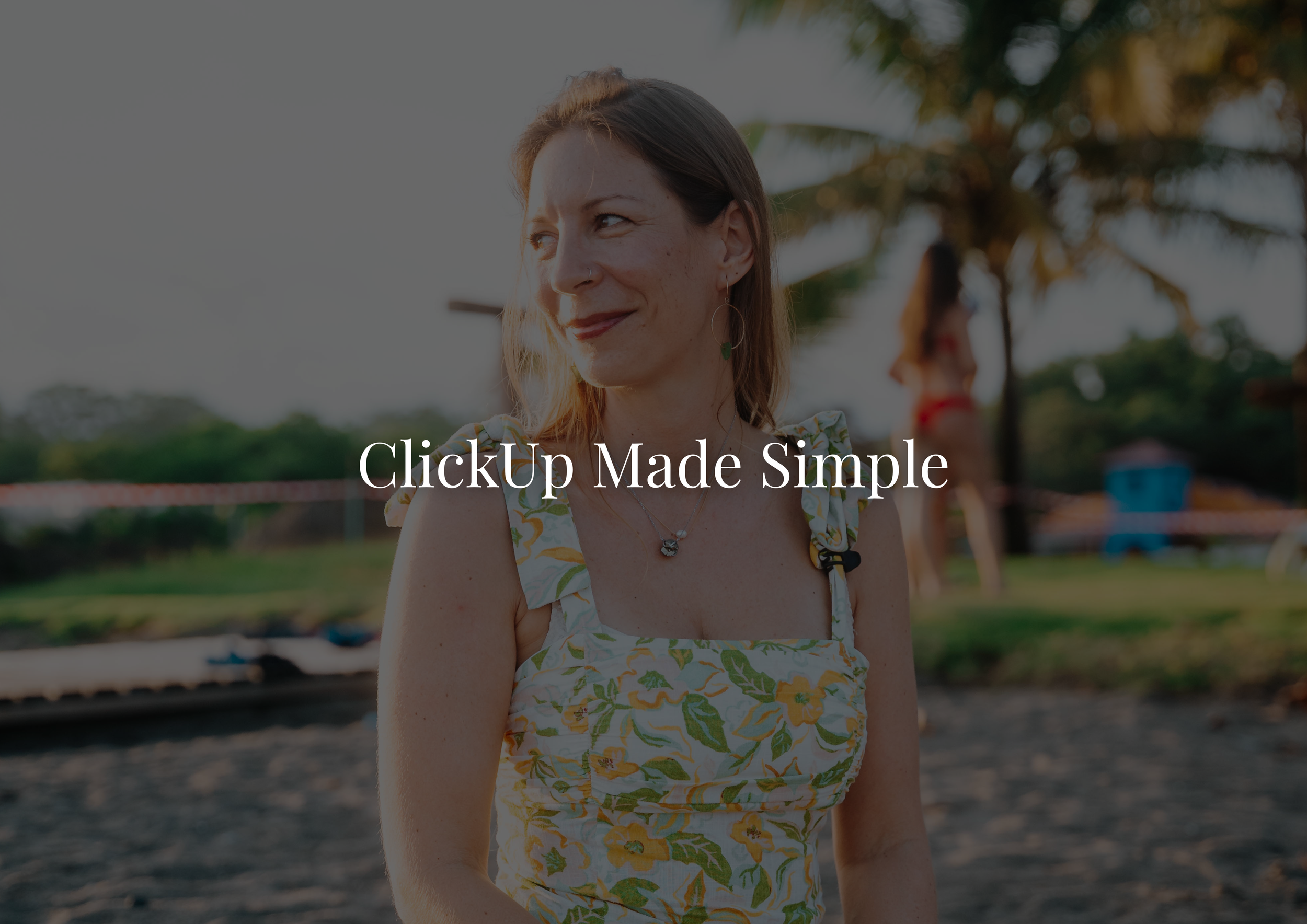 A woman with light brown hair and earrings stands outdoors near water, wearing a floral dress, with palm trees and another person in the background.