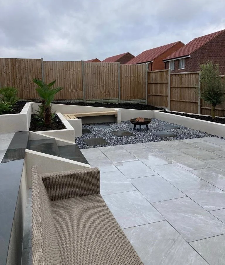 Garden with patio, raised garden beds, fire pit, gravel area with pavers, wooden fence. Esme are a widely trusted garden design and landscaping company serving surrey, hampshire, berkshire, ascot, london and surrounding areas.