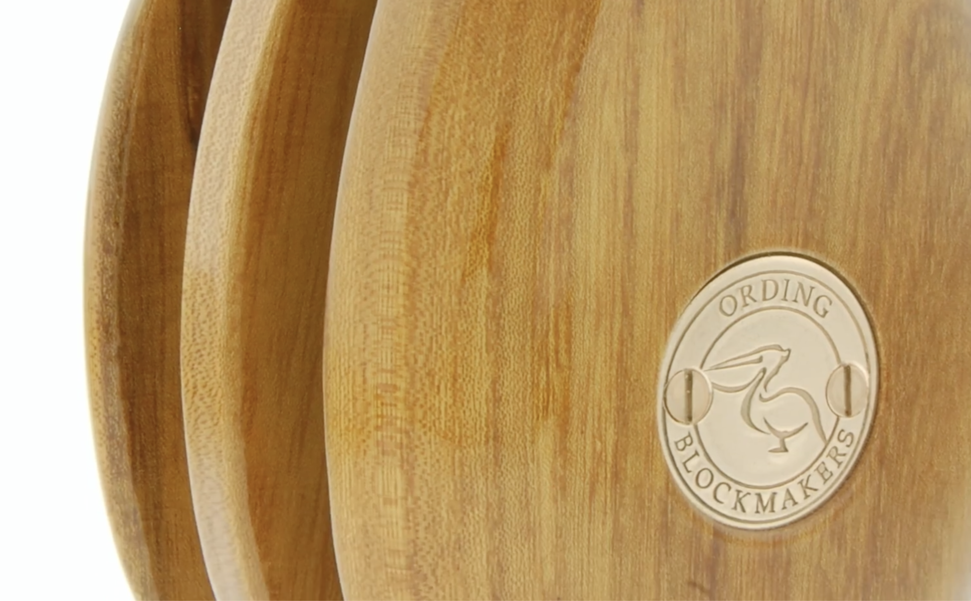 Close-up of a wooden block with a circular metal badge that reads "Ordering Blockmakers"