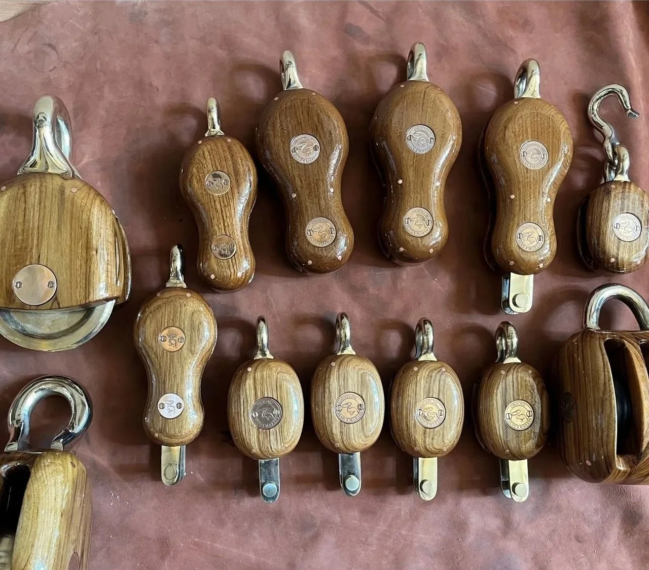A collection of wooden and metal pepper shakers and condiment dispensers arranged on a pink surface.