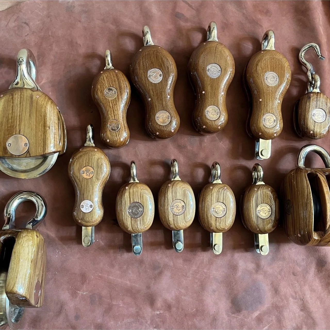 Various wooden-handled and metal tools with hooks and blades, possibly kitchen or industrial tools, laid out on a reddish-brown surface.