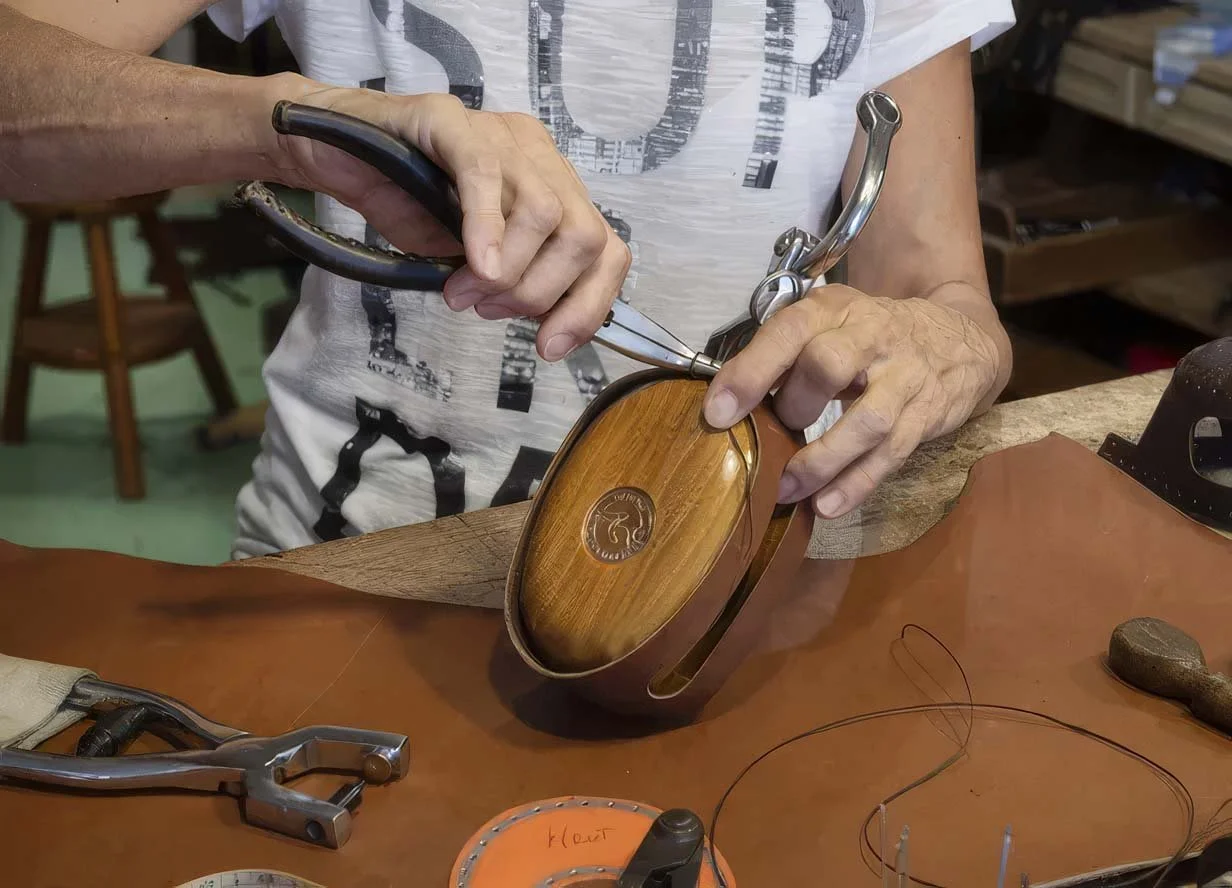 A person working on handcrafted wooden block and leather covering