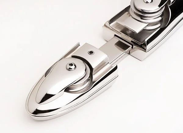 Close-up of a shiny, chrome door hinge against a plain white background.