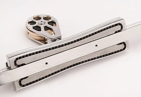 Close-up of a metal linear guide rail and a pulley with wheels.