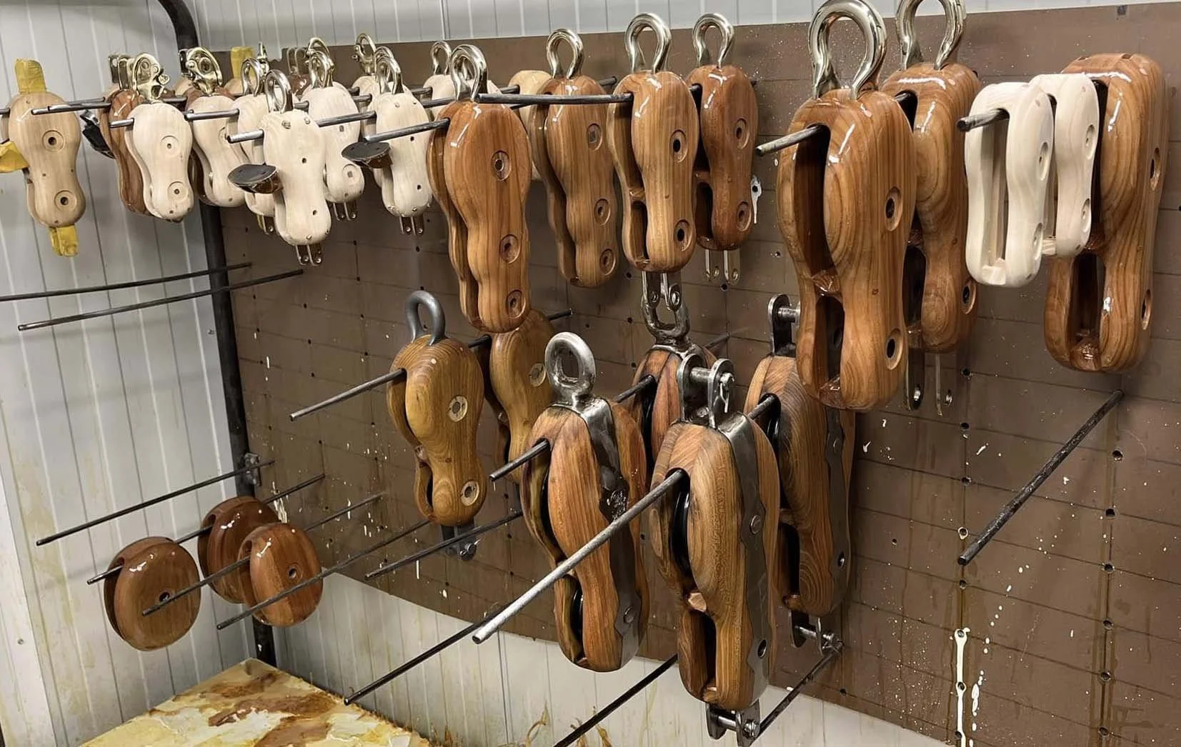 Wooden block being coated in varnish, hanging on hooks, used for woodworking.