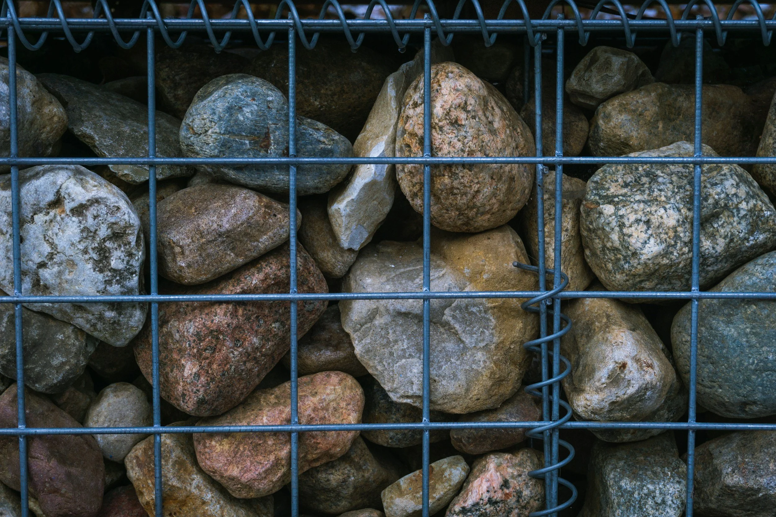Eine Kiste voll mit verschiedenen Steinen, umgeben von Gitterstäben.