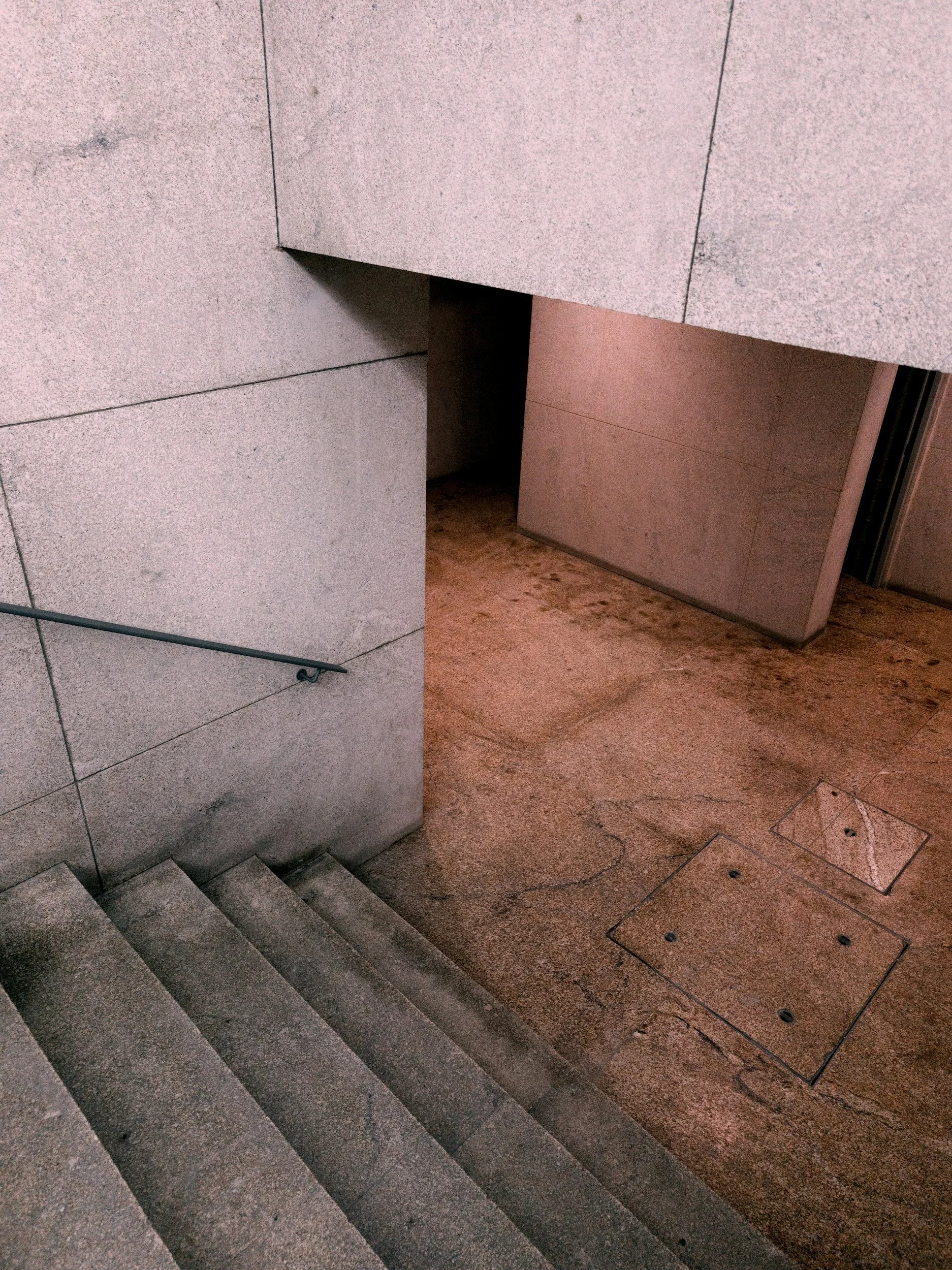 Gebäude mit Stufen und grauen Steinwänden, abwärts verlaufende Treppe, sichtbare Boden- und Wandflächen aus Naturstein.